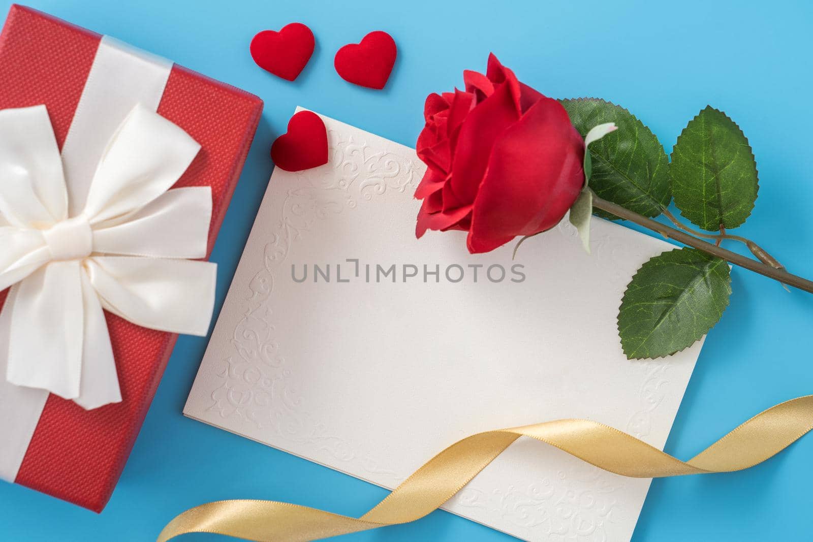 Beautiful greeting card with golden ribbon for Valentine's day, anniversary, mother's day and birthday on blue background, copyspace, topview, mockup, flatlay