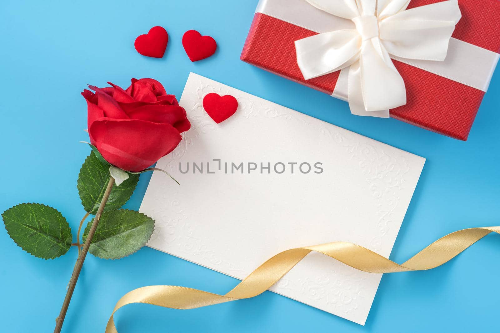 Beautiful greeting card with golden ribbon for Valentine's day, anniversary, mother's day and birthday on blue background, copyspace, topview, mockup, flatlay