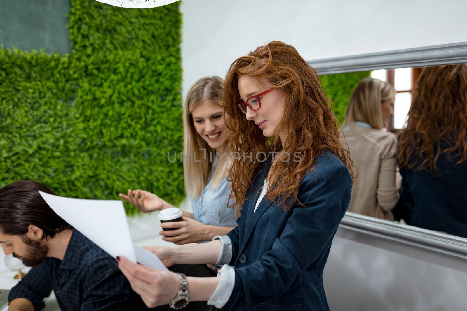 Two business women in a serious discussion standing in the office together looking at paperwork.