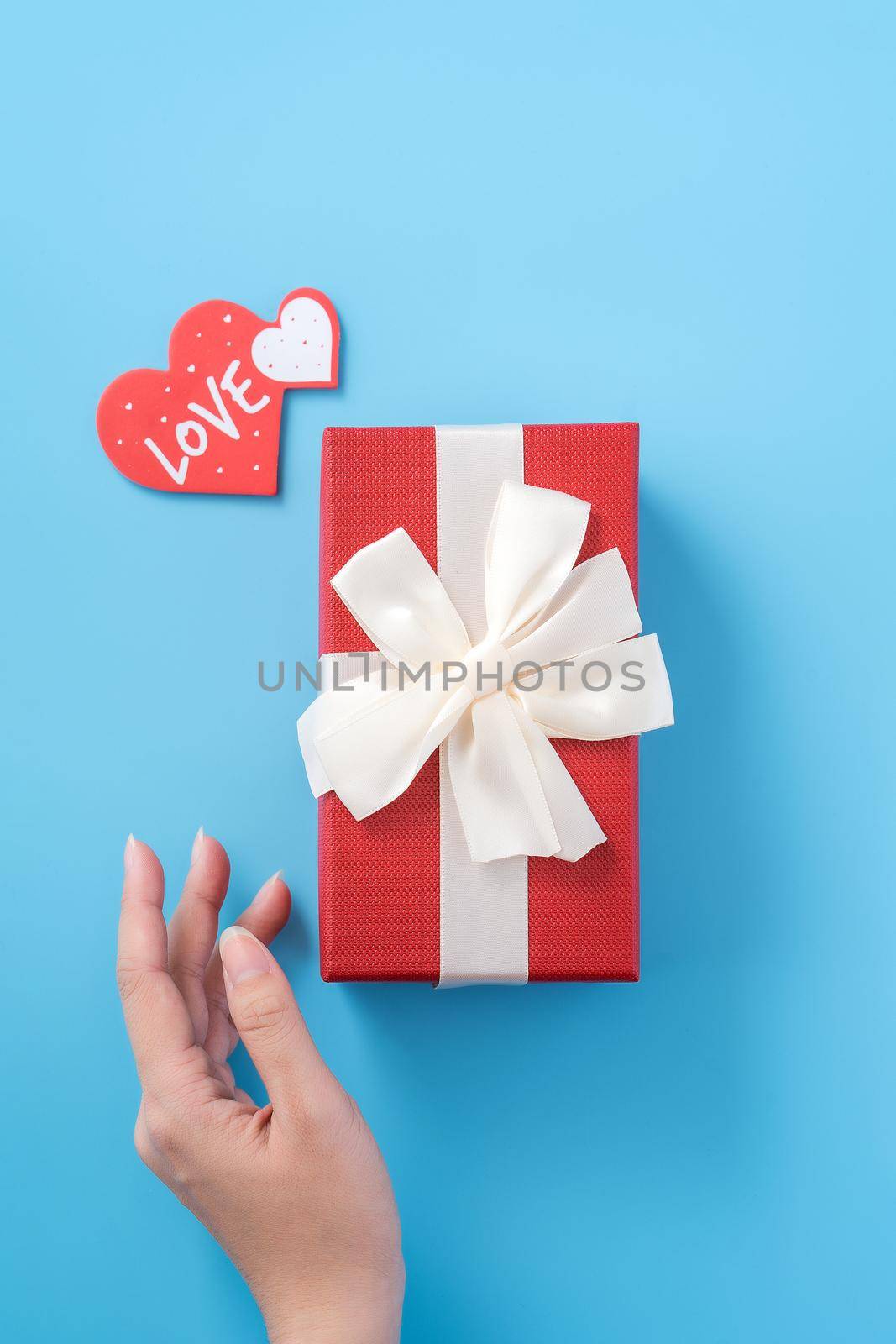A young woman is giving a gift with greeting on blue background, concept of holiday and celebrate for festival surprising, copyspace, topview