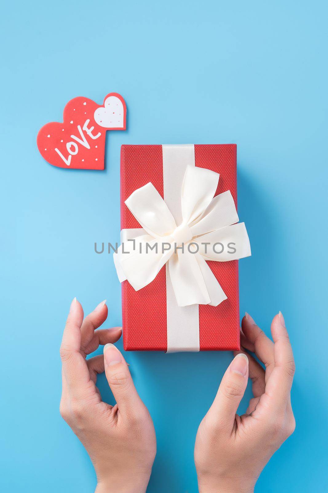 A young woman is giving a gift with greeting on blue background, concept of holiday and celebrate for festival surprising, copyspace, topview