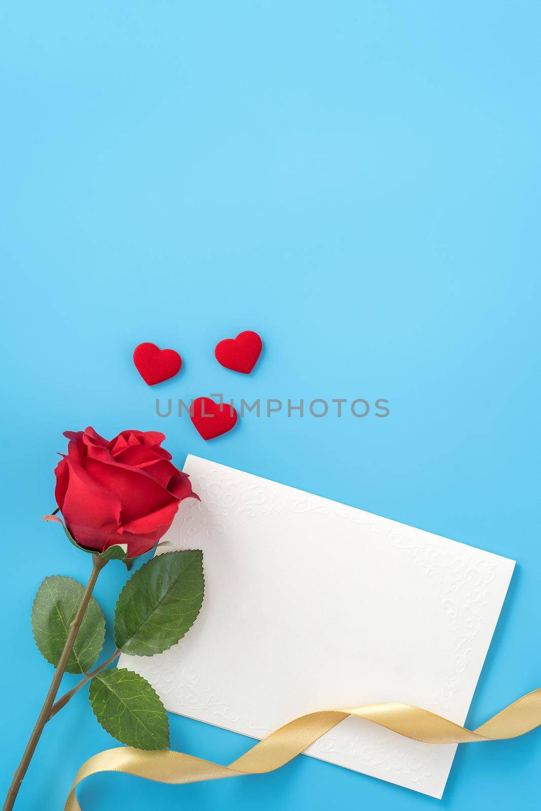 Beautiful greeting card with golden ribbon for Valentine's day, anniversary, mother's day and birthday on blue background, copyspace, topview, mockup, flatlay by ROMIXIMAGE