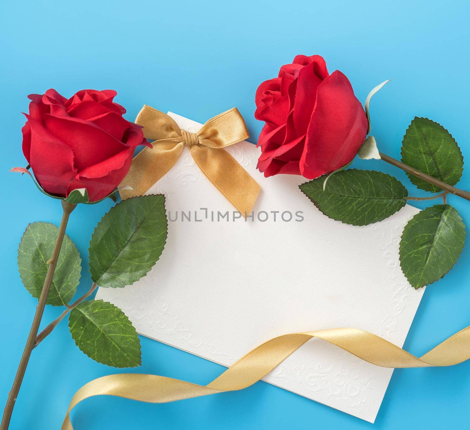 Beautiful greeting card with golden ribbon for Valentine's day, anniversary, mother's day and birthday on blue background, copyspace, topview, mockup, flatlay
