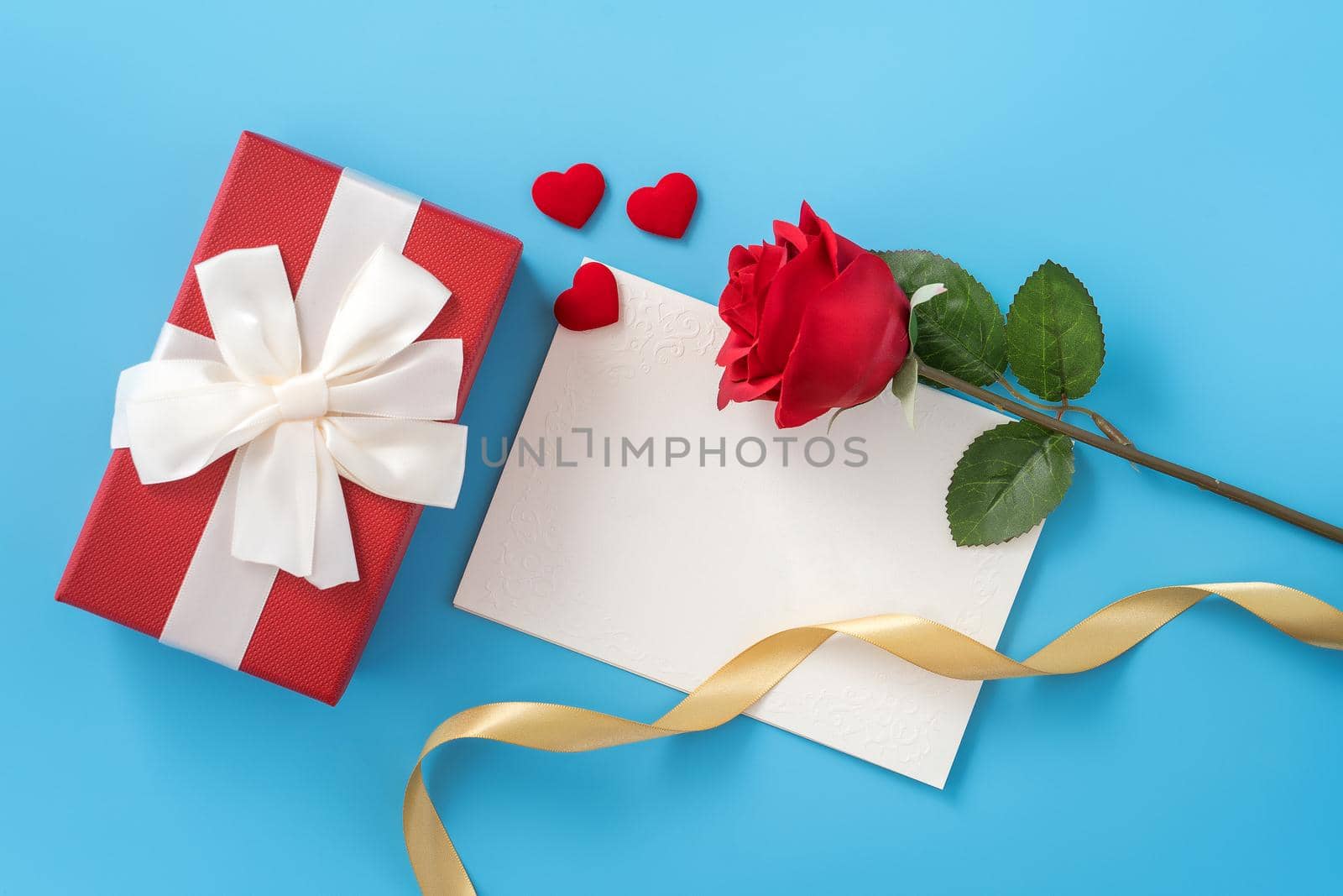 Beautiful greeting card with golden ribbon for Valentine's day, anniversary, mother's day and birthday on blue background, copyspace, topview, mockup, flatlay