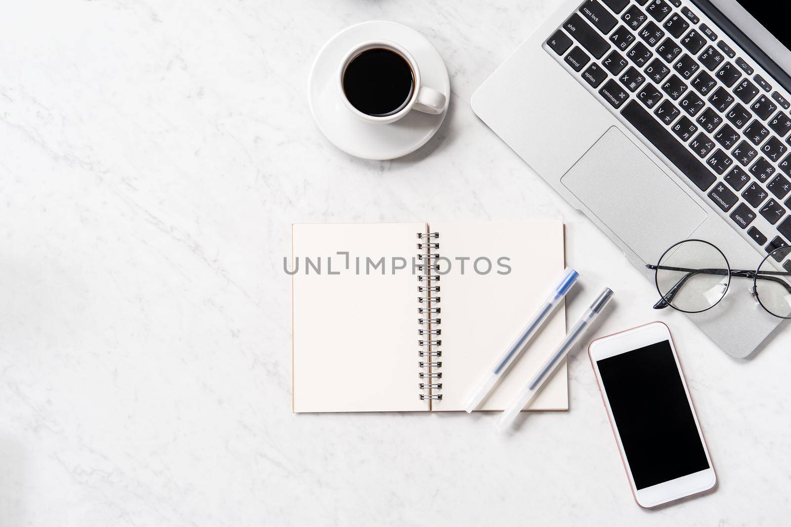 Stylized marble office working desk with smartphone, laptop, glasses and coffee, workspace design, mock up, topview, flatlay, copyspace, closeup