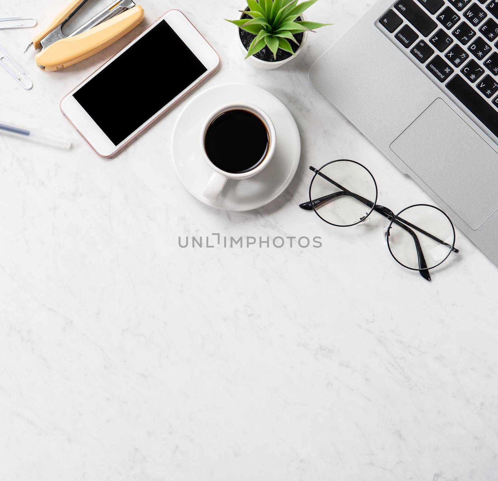 Stylized marble office working desk with smartphone, laptop, glasses and coffee, workspace design, mock up, topview, flatlay, copyspace, closeup