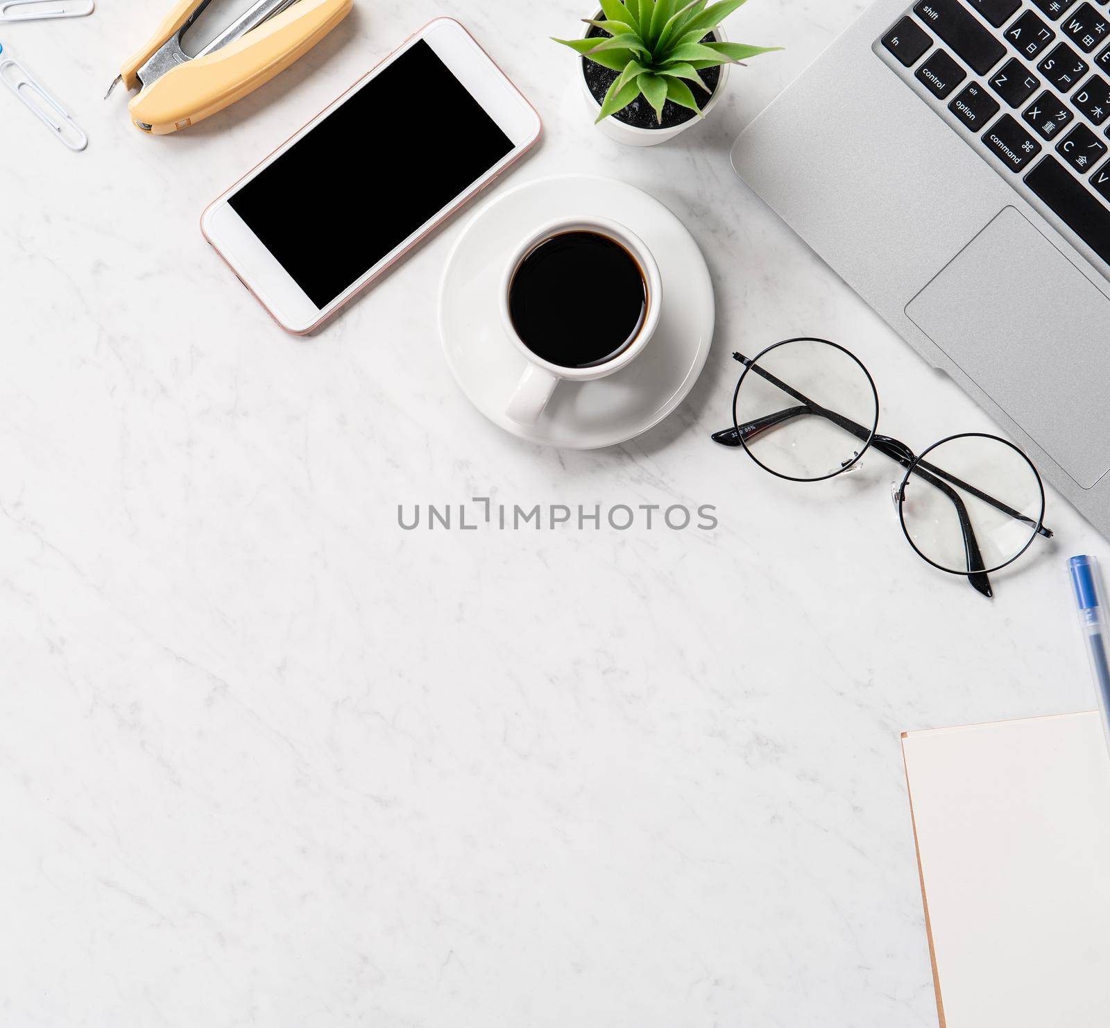 Stylized marble office working desk with smartphone, laptop, glasses and coffee, workspace design, mock up, topview, flatlay, copyspace, closeup