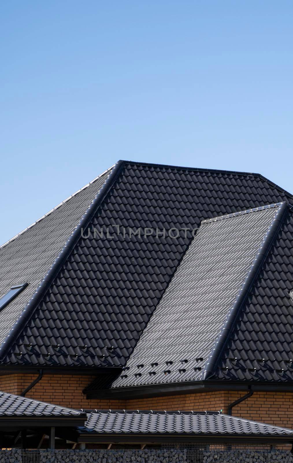 Brown corrugated metal profile roof installed on a modern house. The roof of corrugated sheet. Roofing of metal profile wavy shape. Modern roof made of metal. Metal roofing. by vovsht