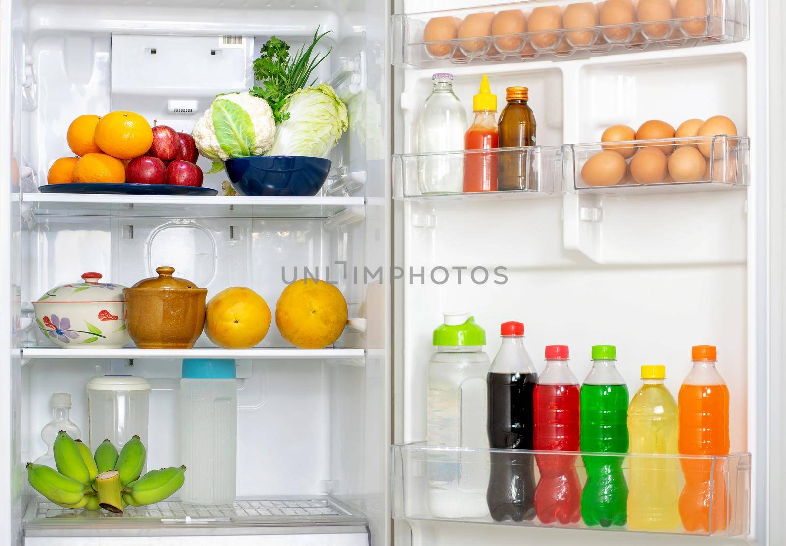 Look into the refrigerator with the lid open a lots of fresh food and drinks inside.