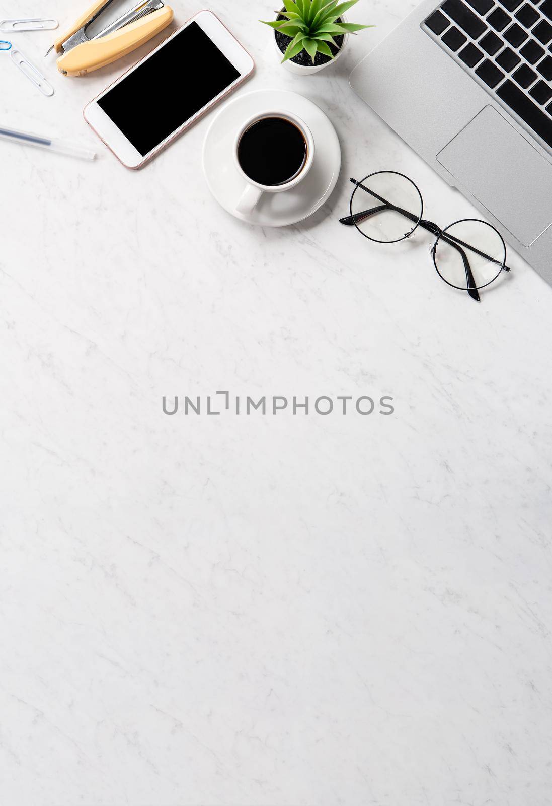Stylized marble office working desk with smartphone, laptop, glasses and coffee, workspace design, mock up, topview, flatlay, copyspace, closeup