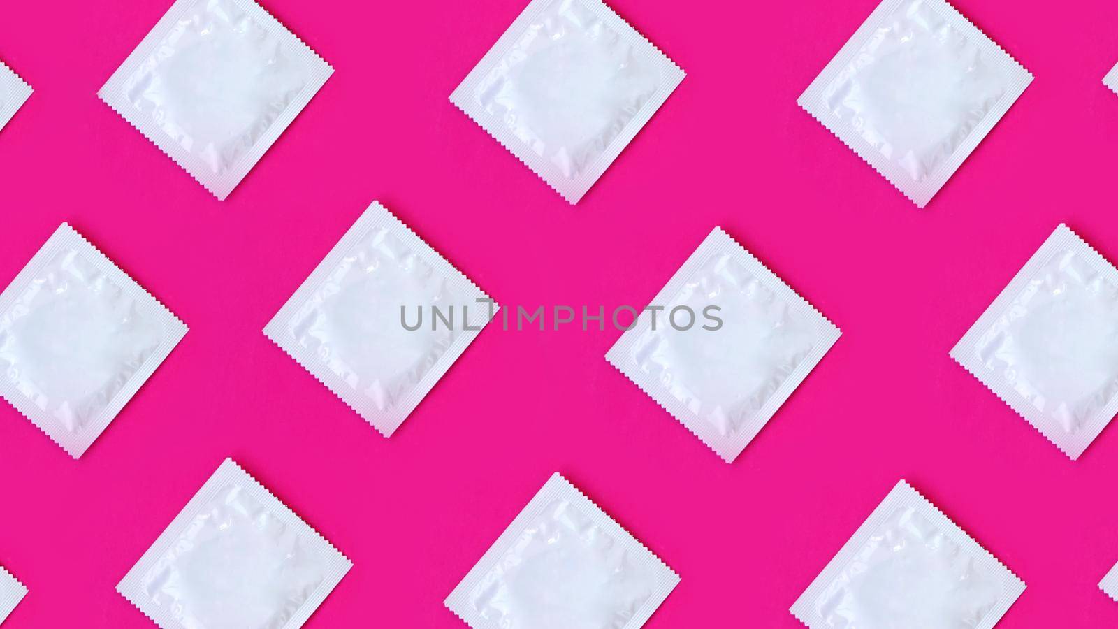 Many condoms in rows on pink background, collection, composition of condoms