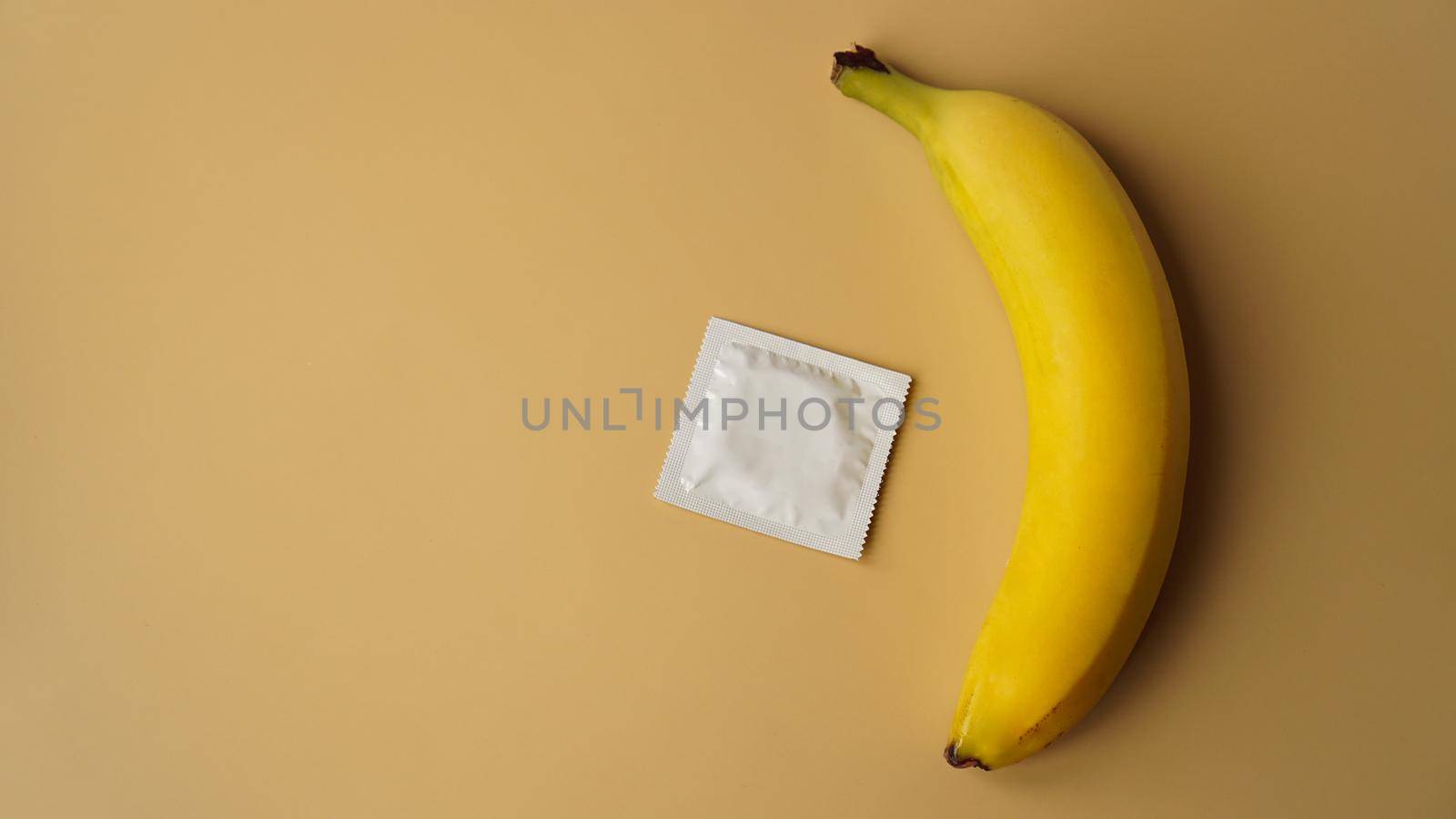 Condoms and banana on golden background, the concept of contraceptives and the prevention of venereal diseases