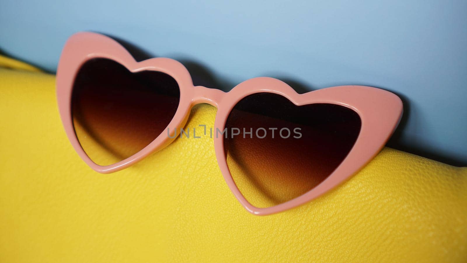 Yellow bag and heart-shaped sunglasses on blue background - summer picture