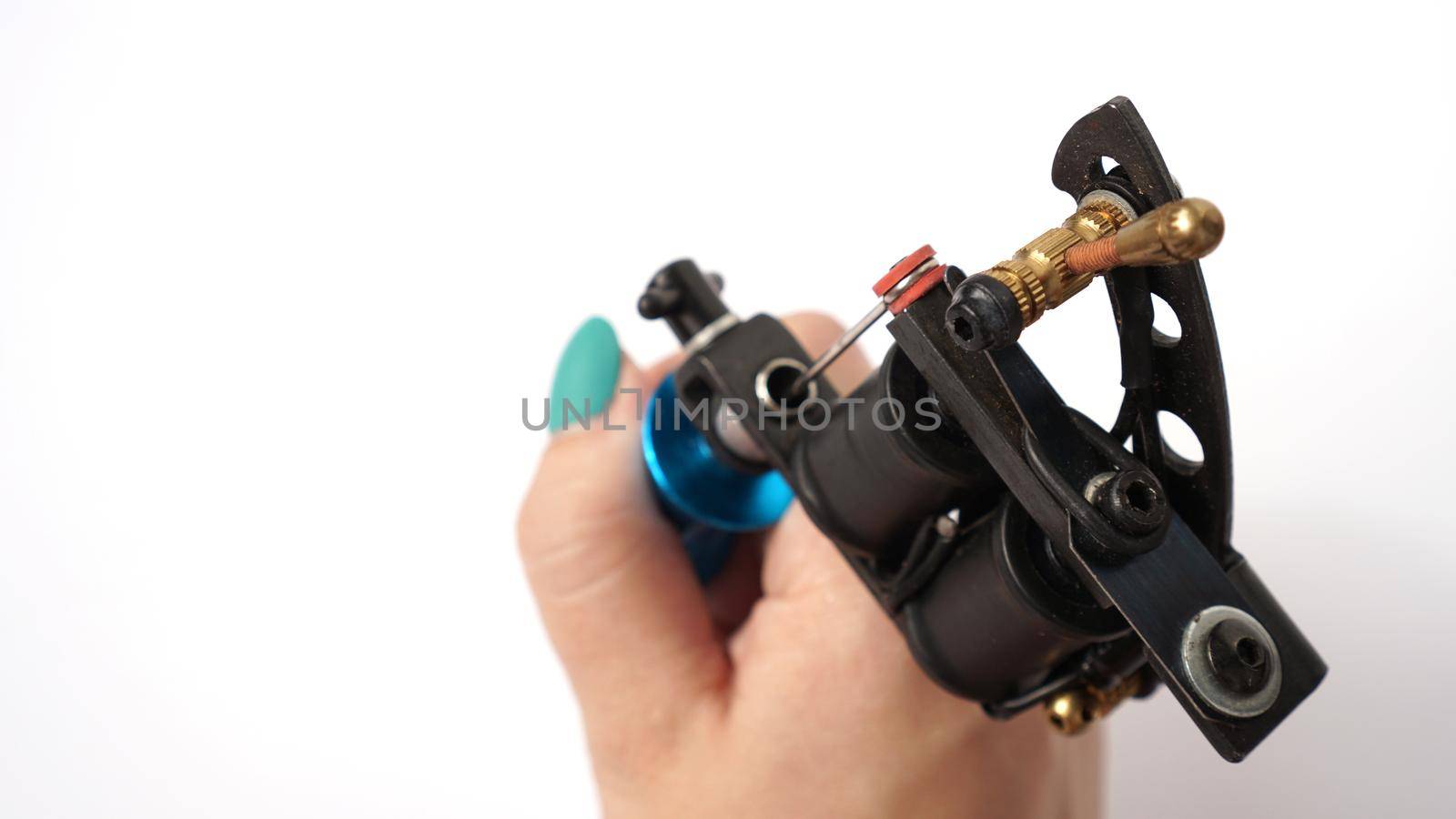 Tattoo machine on tattoo artist hand on white background by natali_brill