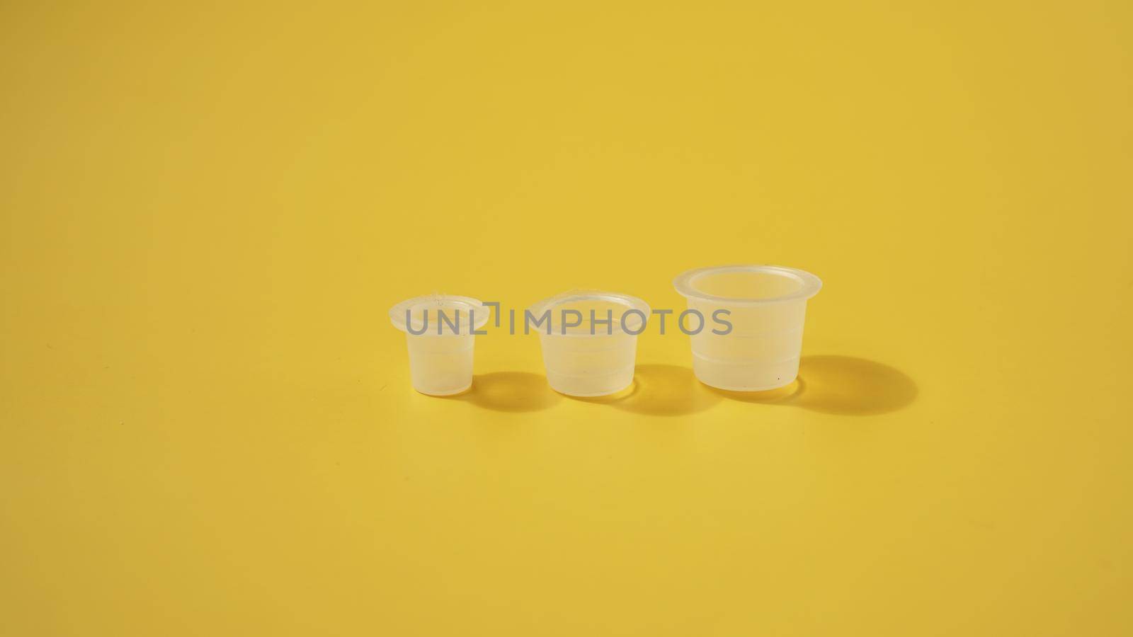 Three ink plastic caps on yellow background - tattoo concept