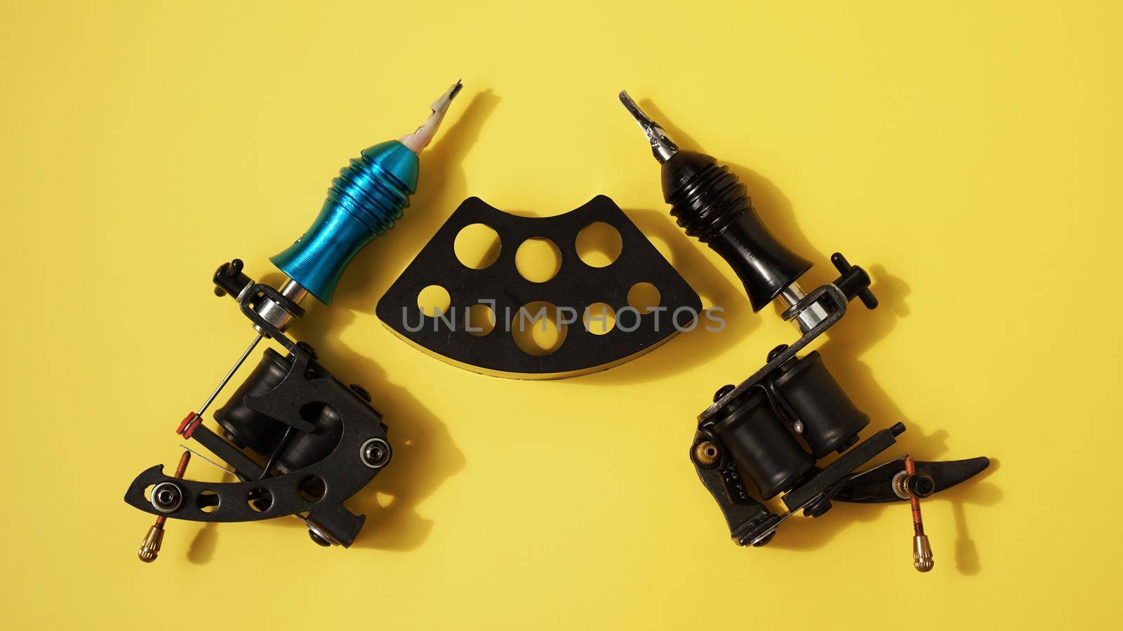 Tattoo equipment, tattoo ink plastic stand for tattoo ink caps and tattoo machines on yellow background