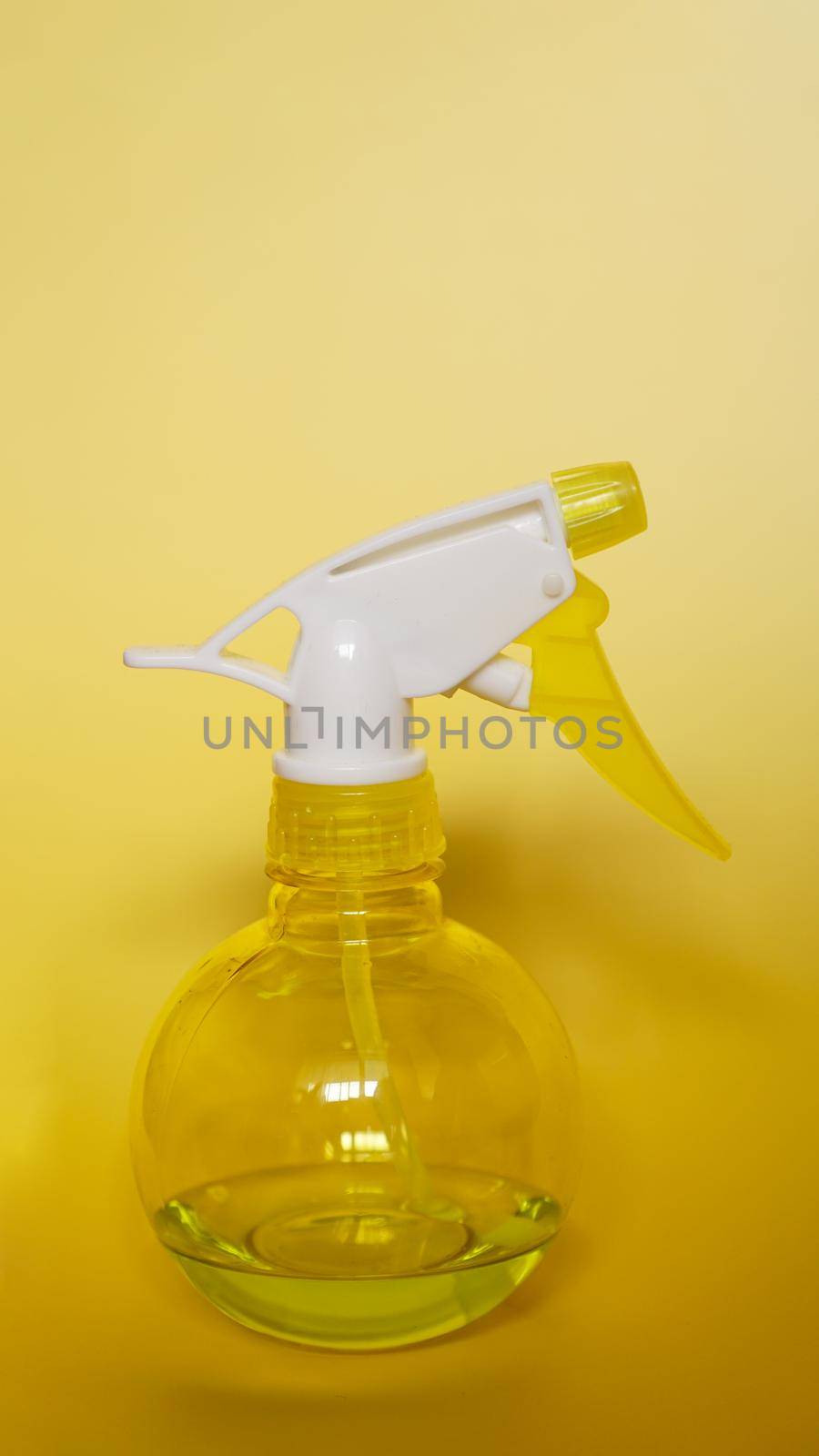 Spray bottle on yellow background. Portable pressure water sprayer pump. Sprayer bottle - vertical photo