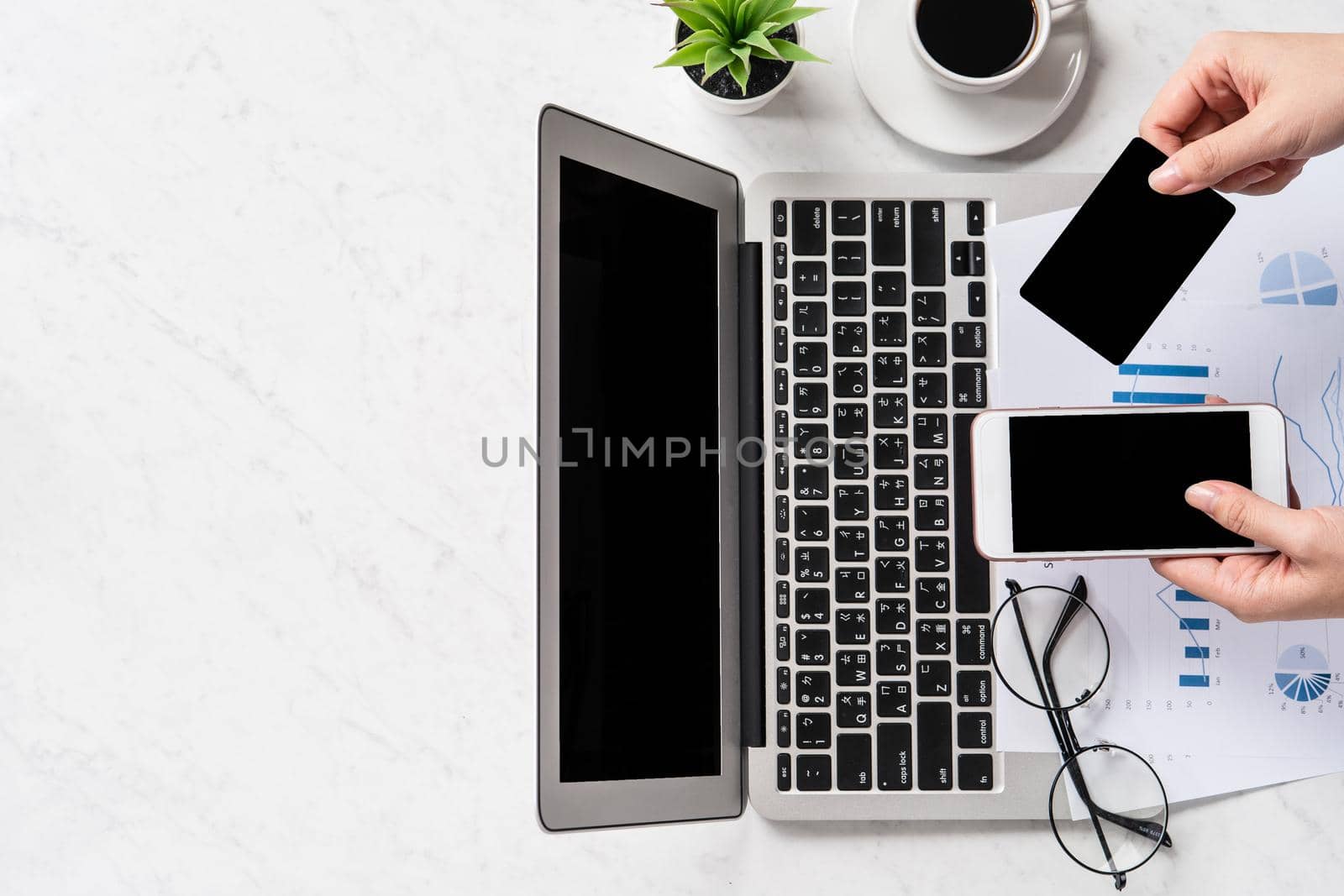 A woman is doing a online payment or shopping, mock up credit card and mobile phone on office desk isolated on beautiful fashion marble background, topview, flatlay, copyspace.