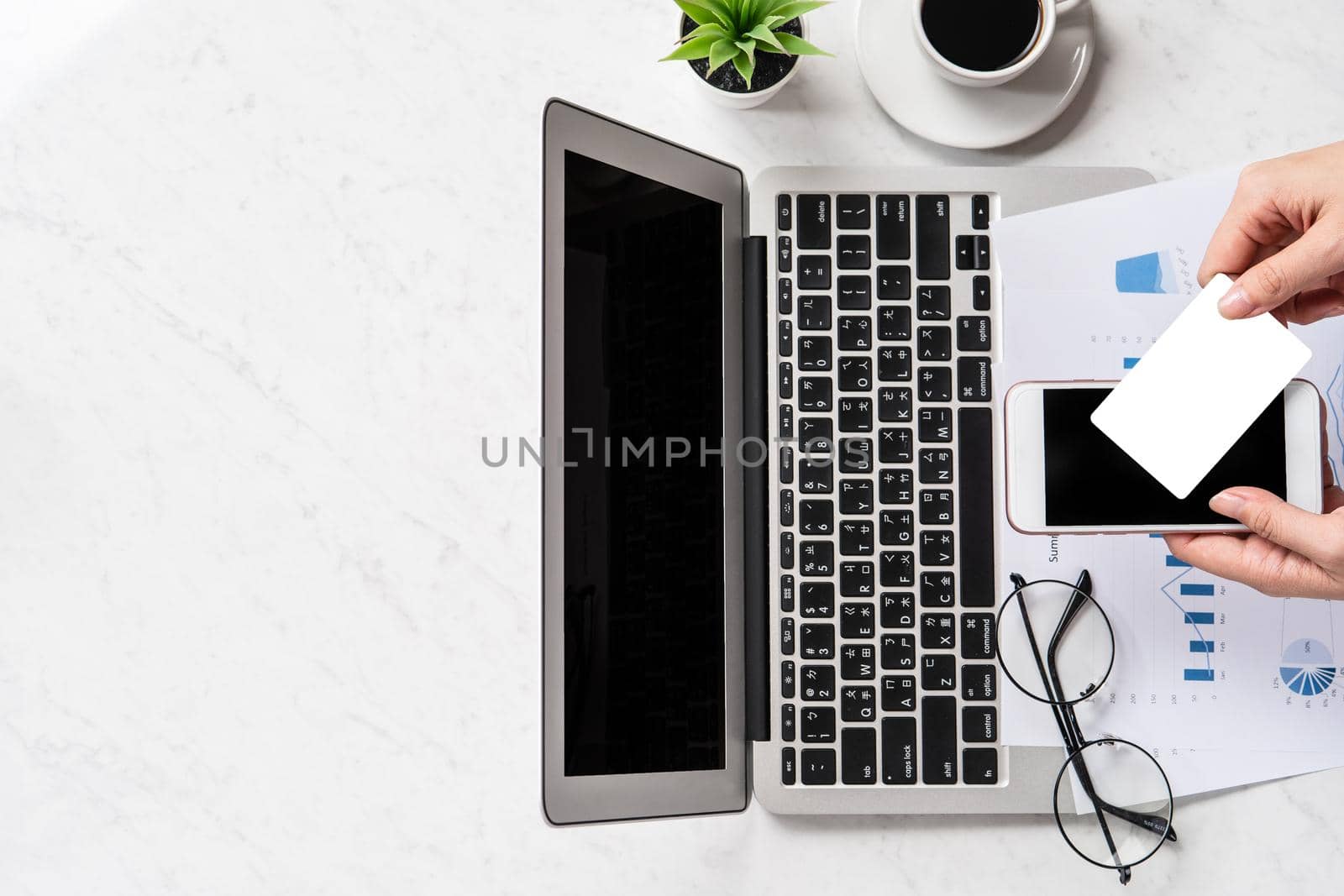 A woman is doing a online payment or shopping, mock up credit card and mobile phone on office desk isolated on beautiful fashion marble background, topview, flatlay, copyspace.