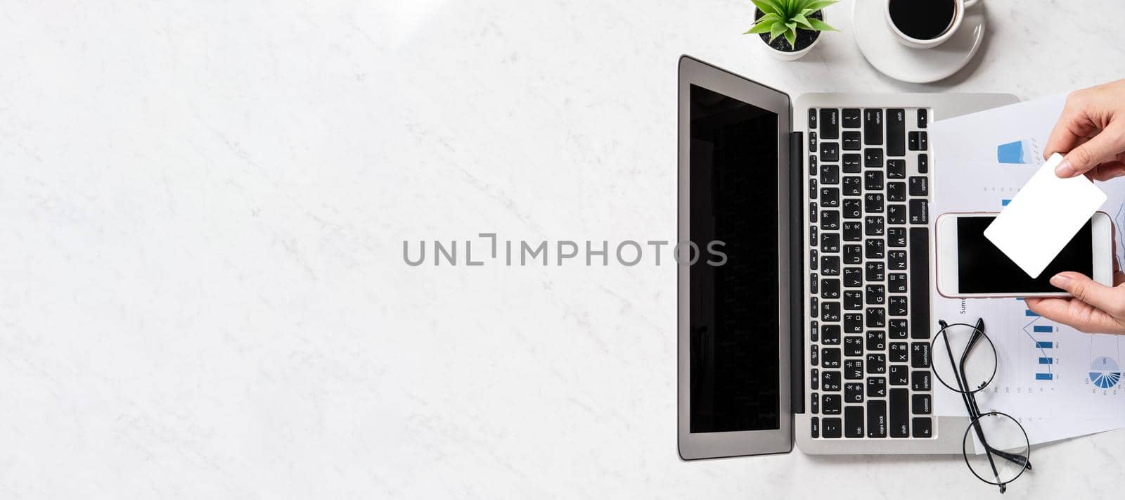 A woman is doing a online payment or shopping, mock up credit card and mobile phone on office desk isolated on beautiful fashion marble background, topview, flatlay, copyspace. by ROMIXIMAGE