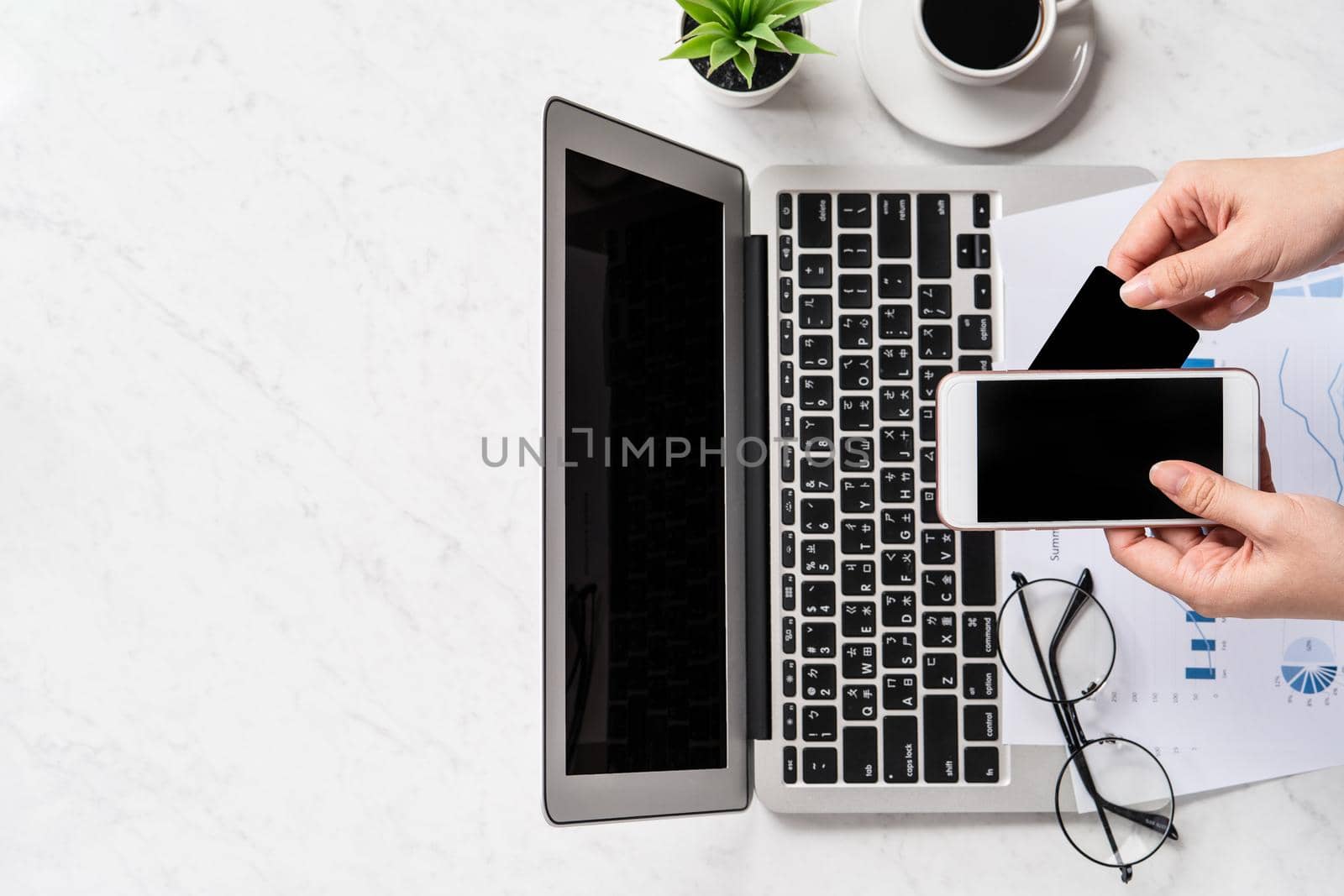 A woman is doing a online payment or shopping, mock up credit card and mobile phone on office desk isolated on beautiful fashion marble background, topview, flatlay, copyspace.