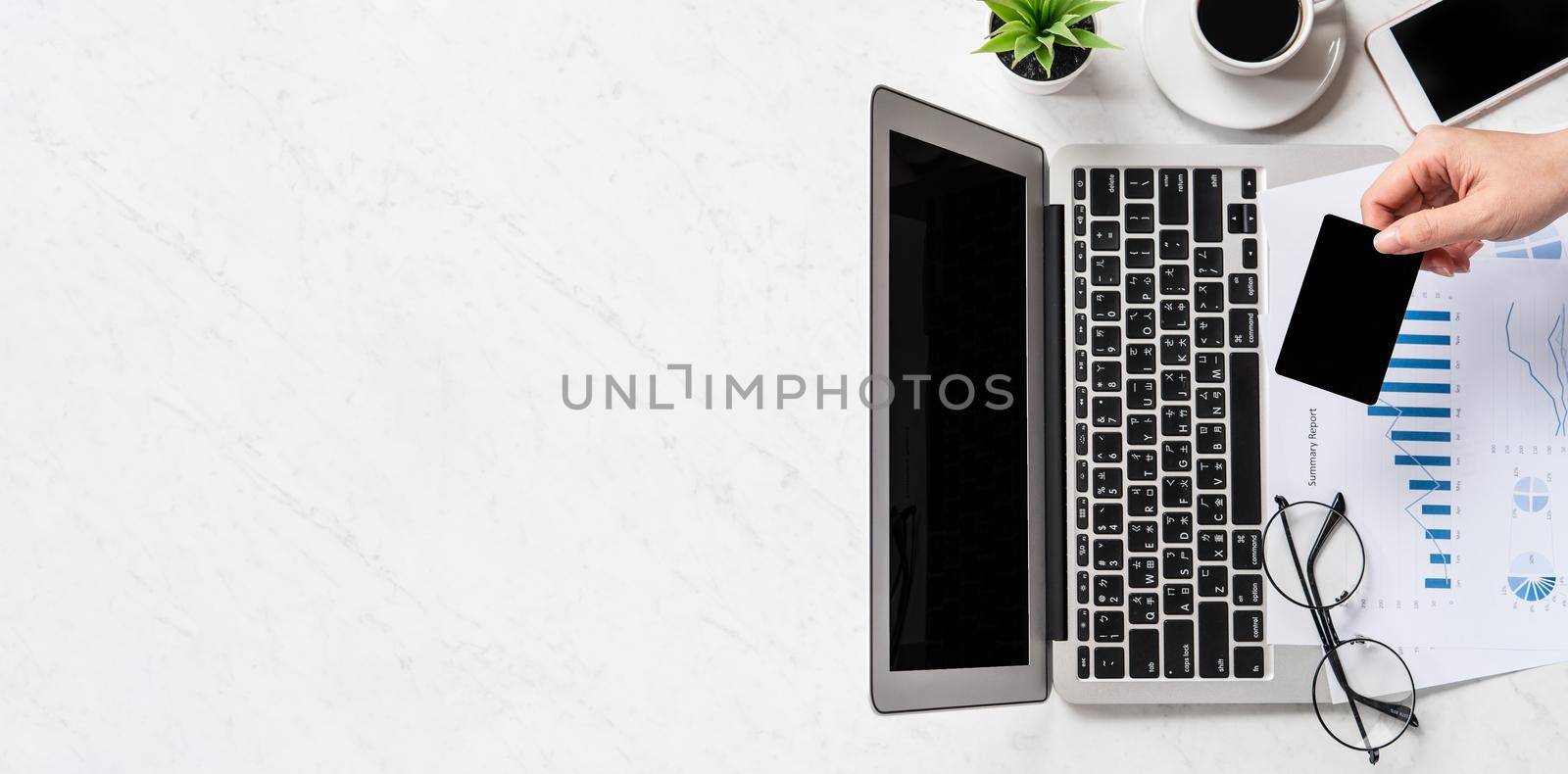 A woman is doing a online payment or shopping, mock up credit card and mobile phone on office desk isolated on beautiful fashion marble background, topview, flatlay, copyspace. by ROMIXIMAGE
