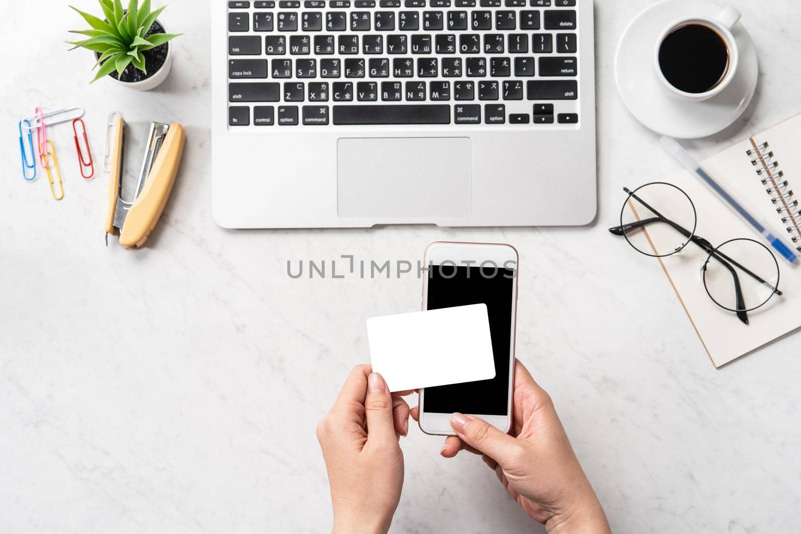 A woman is doing a online purchase, mock up credit card and mobile cellphone on office desk isolated on beautiful fashion marble background, copy space, topview, flatlay, closeup