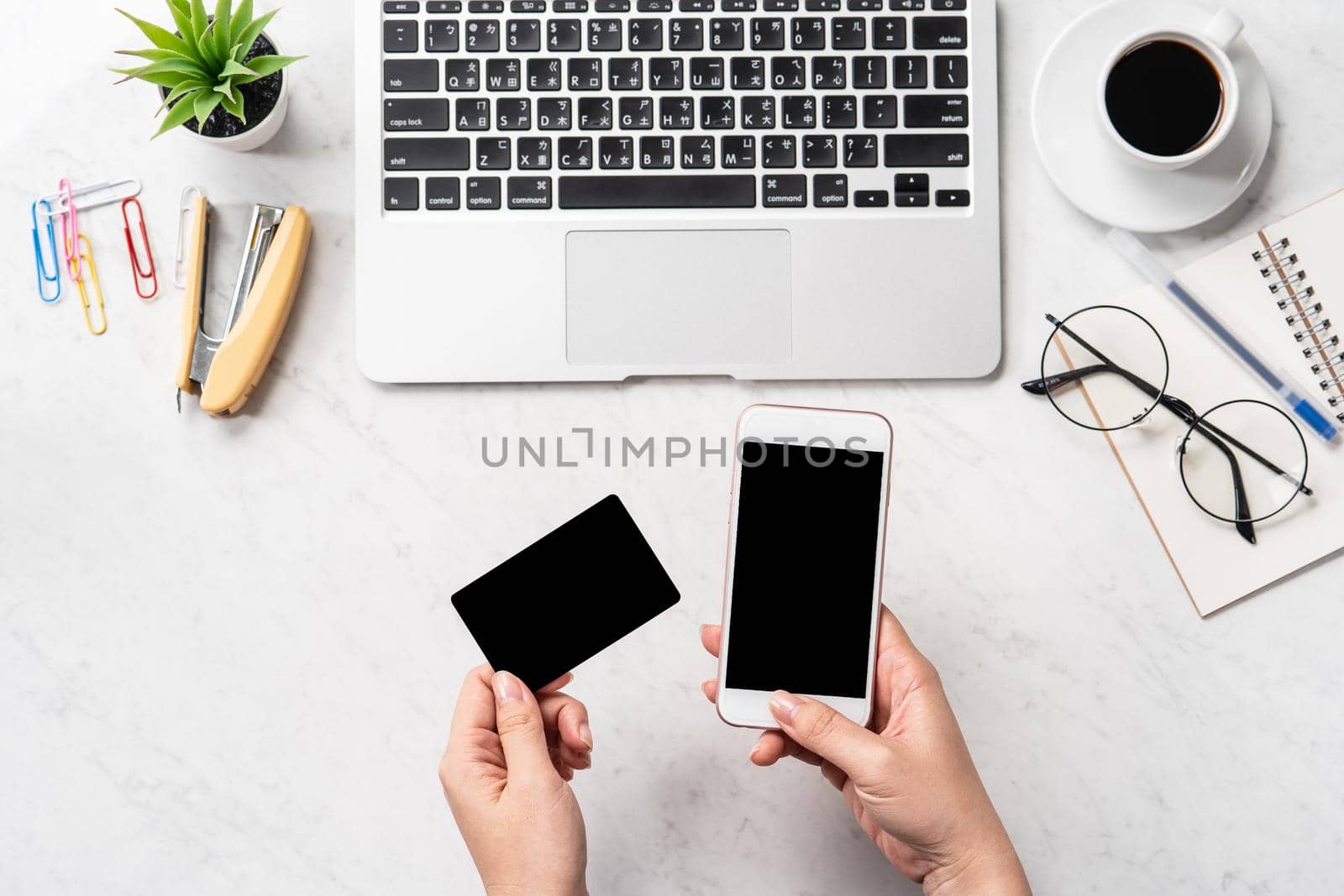A woman is doing a online purchase, mock up credit card and mobile cellphone on office desk isolated on beautiful fashion marble background, copy space, topview, flatlay, closeup