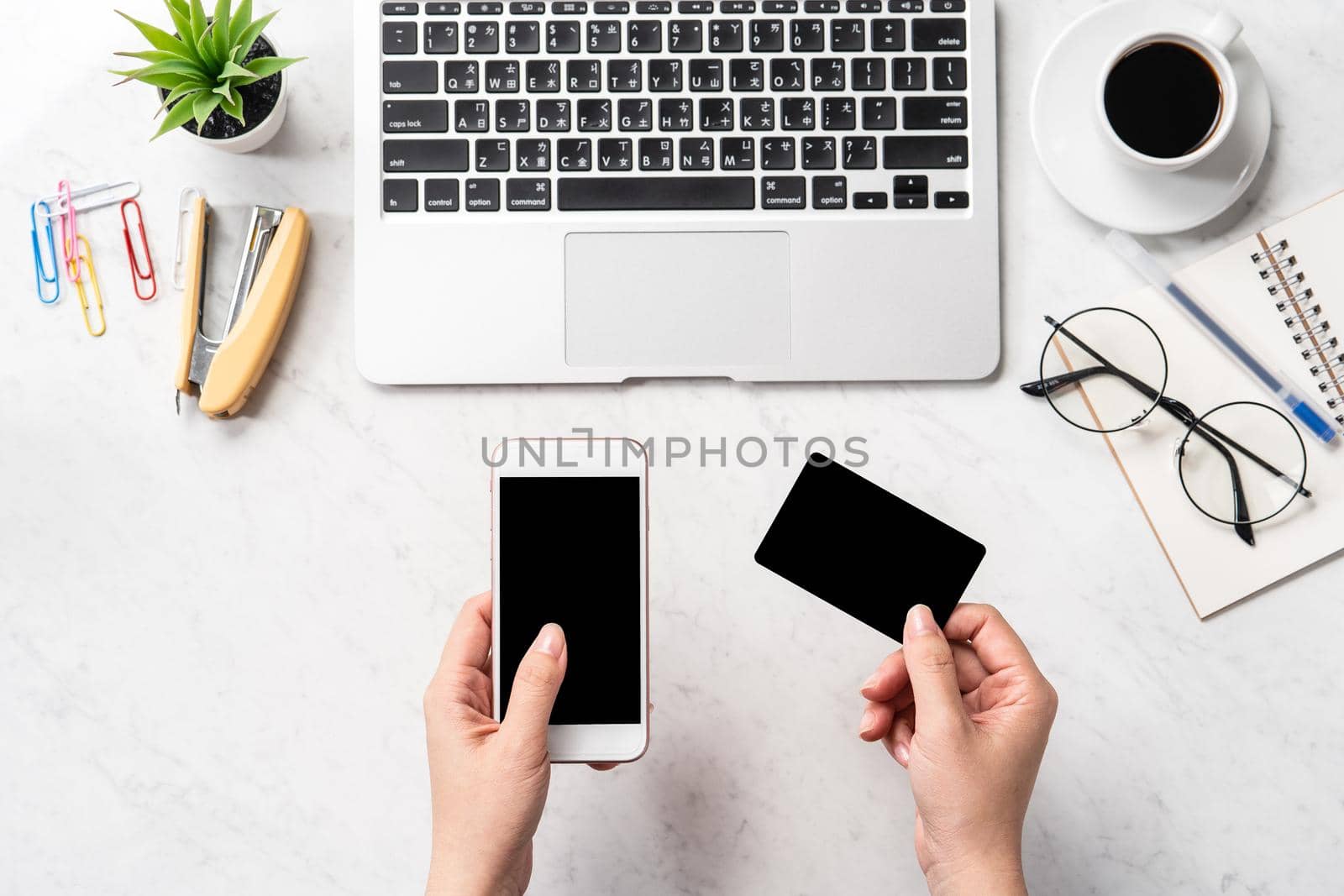 A woman is doing a online purchase, mock up credit card and mobile cellphone on office desk isolated on beautiful fashion marble background, copy space, topview, flatlay, closeup