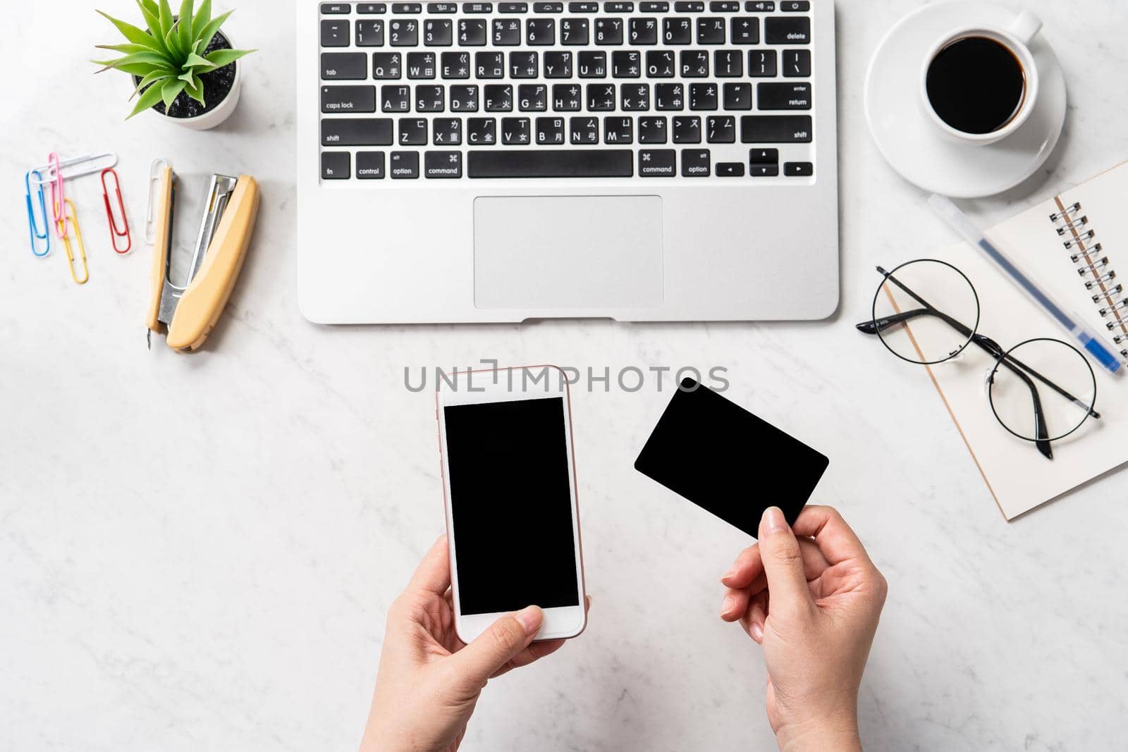 A woman is doing a online purchase, mock up credit card and mobile cellphone on office desk isolated on beautiful fashion marble background, copy space, topview, flatlay, closeup