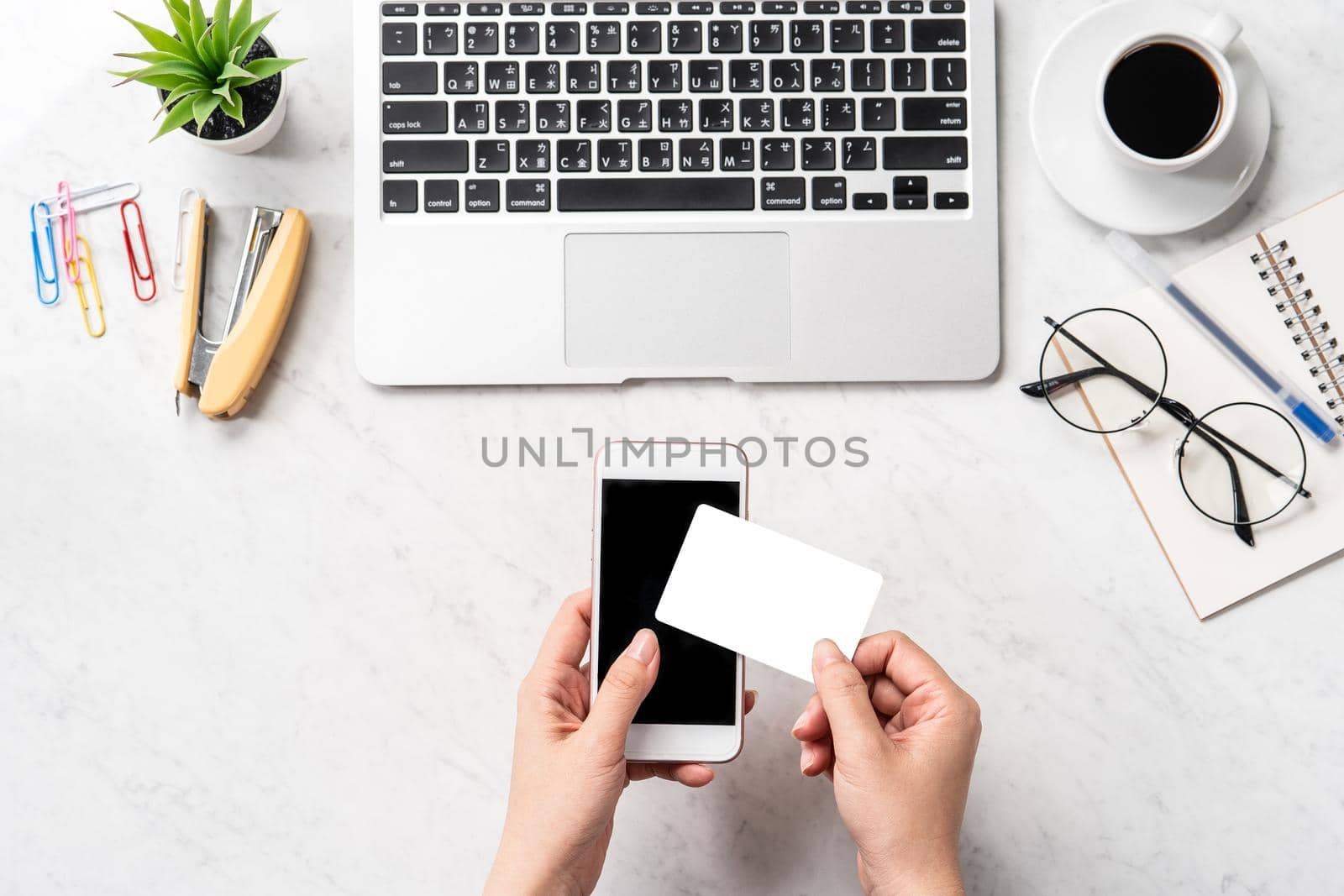A woman is doing a online purchase, mock up credit card and mobile cellphone on office desk isolated on beautiful fashion marble background, copy space, topview, flatlay, closeup