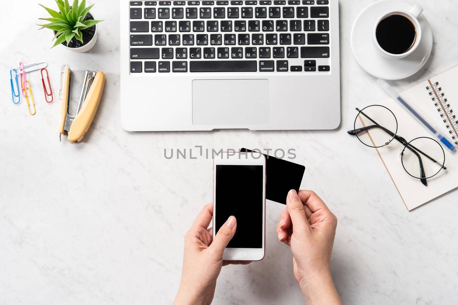 A woman is doing a online purchase, mock up credit card and mobile cellphone on office desk isolated on beautiful fashion marble background, copy space, topview, flatlay, closeup