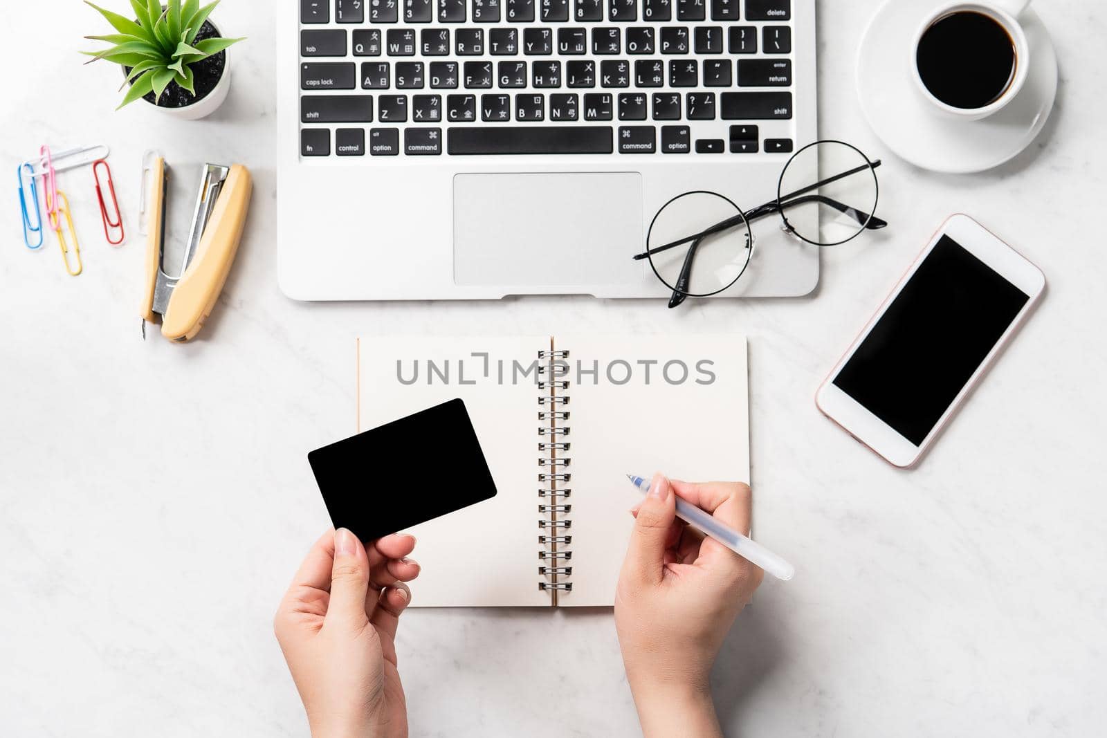A woman is doing a online purchase, mock up credit card and mobile cellphone on office desk isolated on beautiful fashion marble background, copy space, topview, flatlay, closeup
