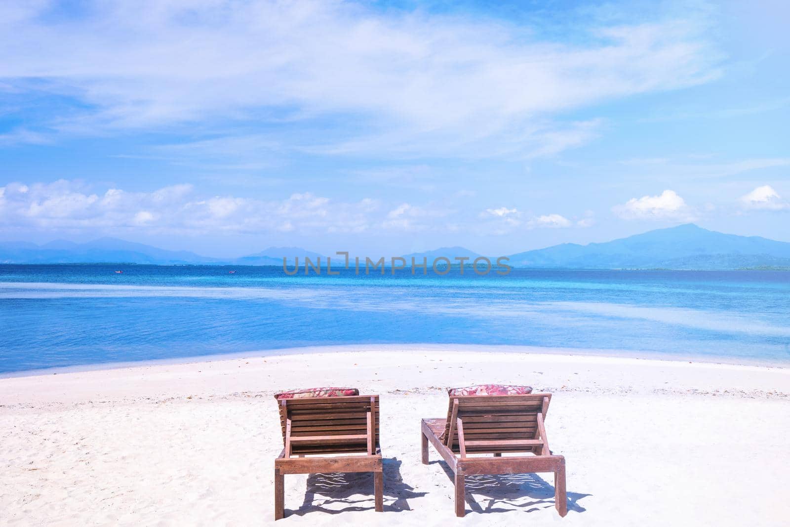 Chairs on the amazing beautiful sandy beach near the ocean with blue sky. Concept of summer leisure calm vacation for a tourism idea. Empty copy space, inspiration of tropical landscape