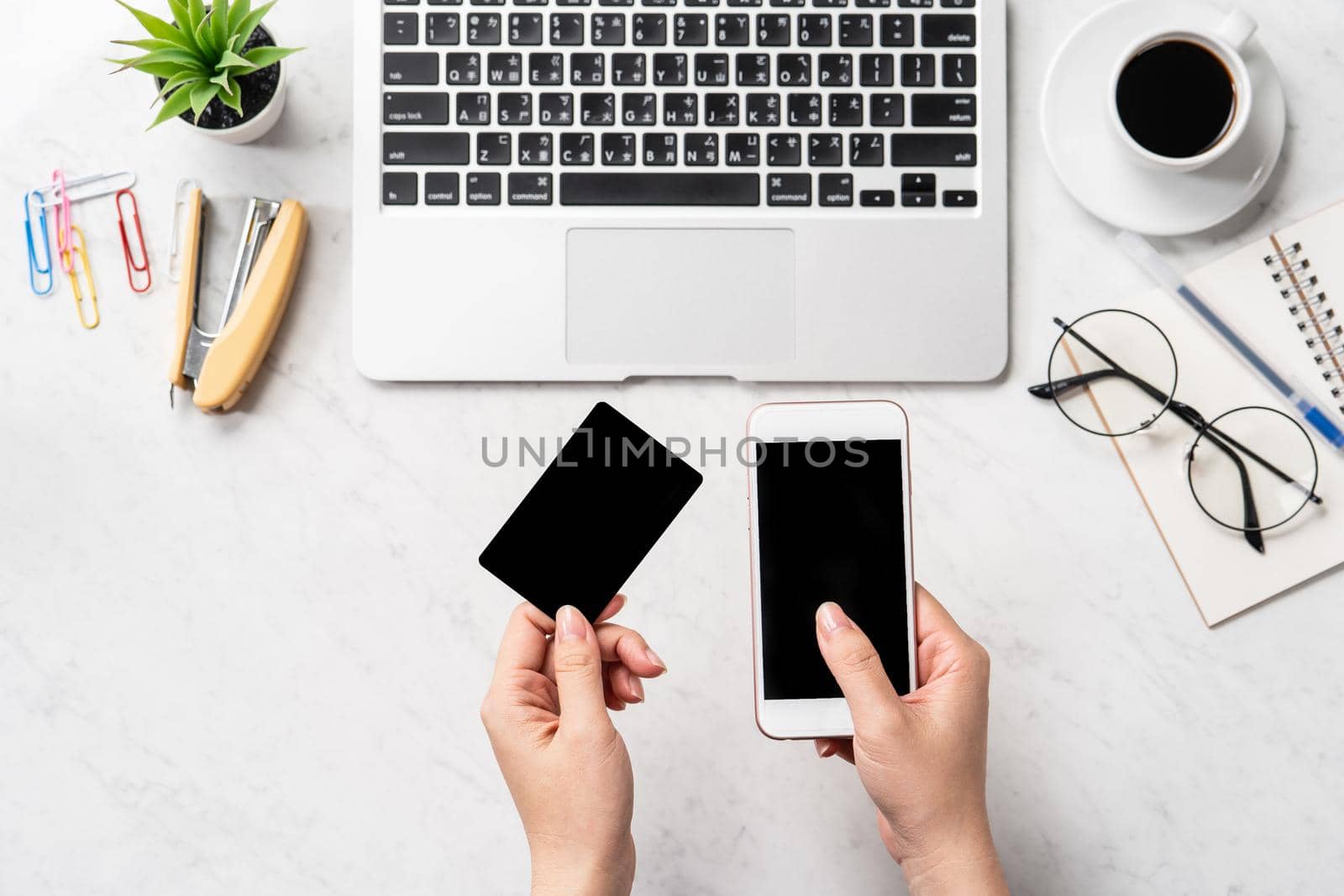 A woman is doing a online purchase, mock up credit card and mobile cellphone on office desk isolated on beautiful fashion marble background, copy space, topview, flatlay, closeup