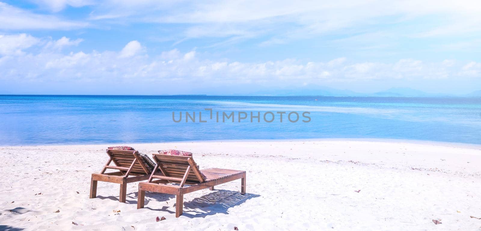 Chairs on the amazing beautiful sandy beach near the ocean with blue sky. Concept of summer leisure calm vacation for a tourism idea. Empty copy space, inspiration of tropical landscape