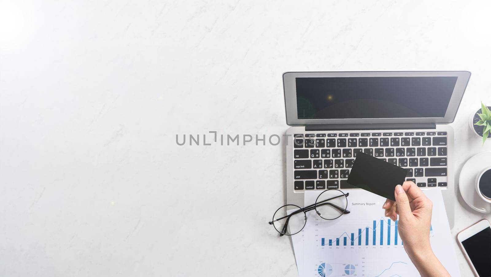 Concept of a woman is doing a online purchase, mock up card and cellphone on office desk isolated on beautiful fashion marble background, copy space, top view, flat lay, closeup