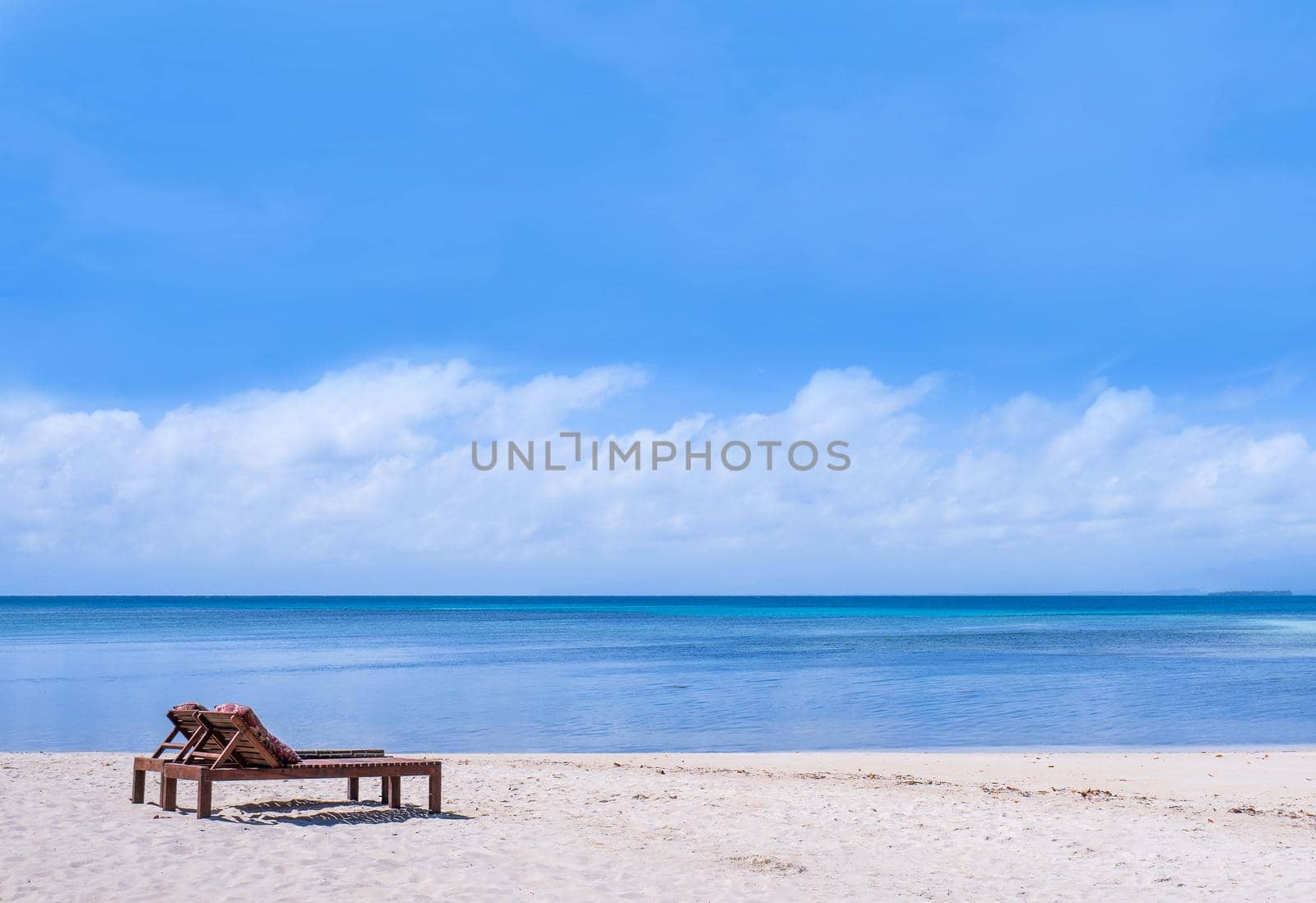 Chairs on the amazing beautiful sandy beach near the ocean with blue sky. Concept of summer leisure calm vacation for a tourism idea. Empty copy space, inspiration of tropical landscape