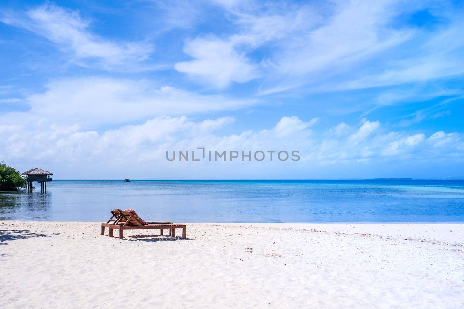 Chairs on the amazing beautiful sandy beach near the ocean with blue sky. Concept of summer leisure calm vacation for a tourism idea. Empty copy space, inspiration of tropical landscape