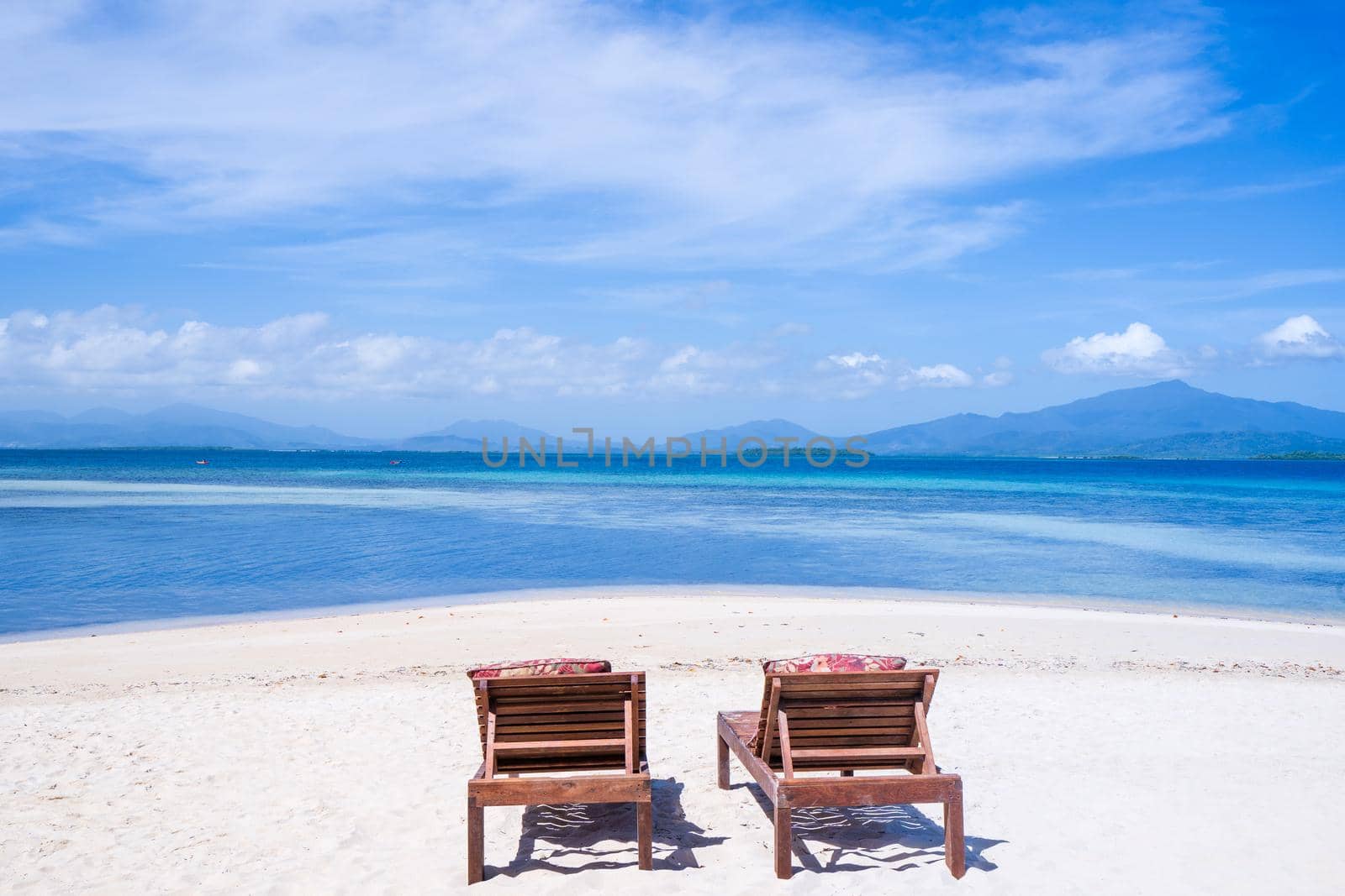 Chairs on the amazing beautiful sandy beach near the ocean with blue sky. Concept of summer leisure calm vacation for a tourism idea. Empty copy space, inspiration of tropical landscape