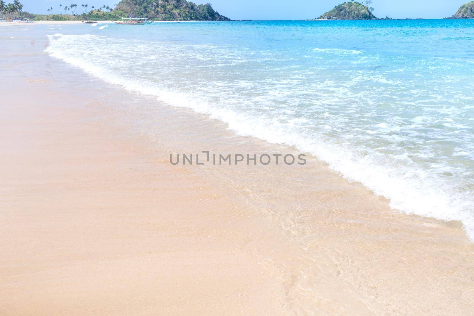 Beautiful amazing gold colored sandy beach with soft waves isolated with sunny blue sky. Concept of tropical calm tourism idea, copy space, close up