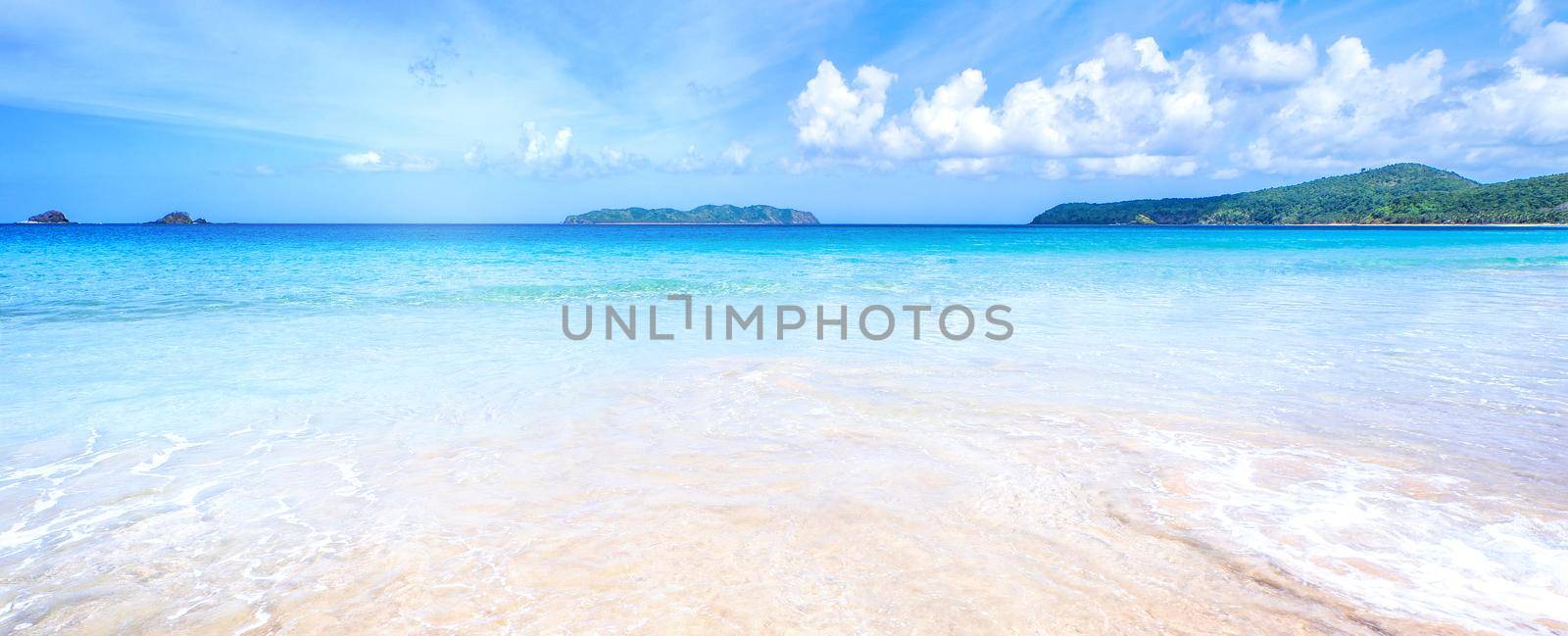 Beautiful amazing gold colored sandy beach with soft waves isolated with sunny blue sky. Concept of tropical calm tourism idea, copy space, close up