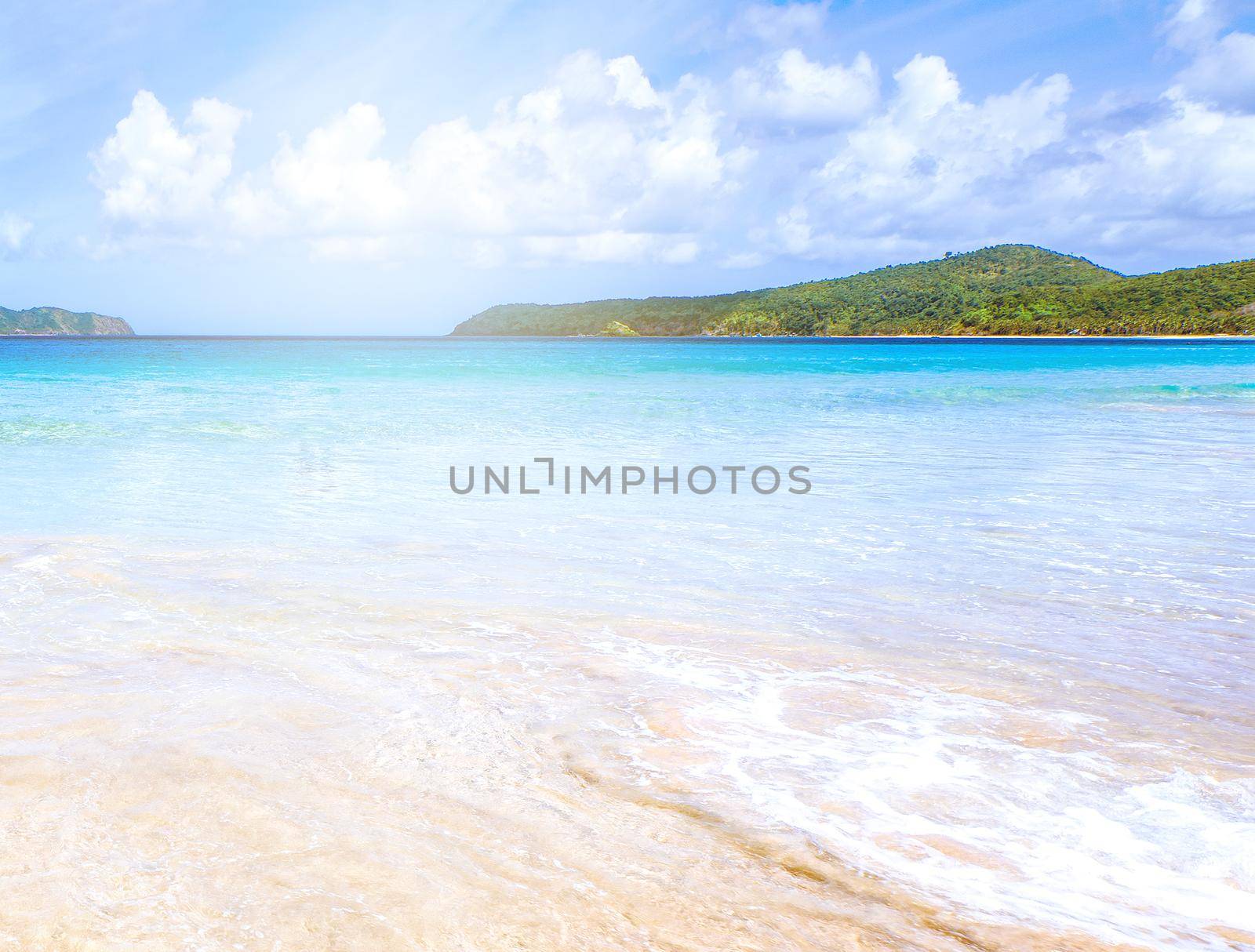 Beautiful amazing gold colored sandy beach with soft waves isolated with sunny blue sky. Concept of tropical calm tourism idea, copy space, close up