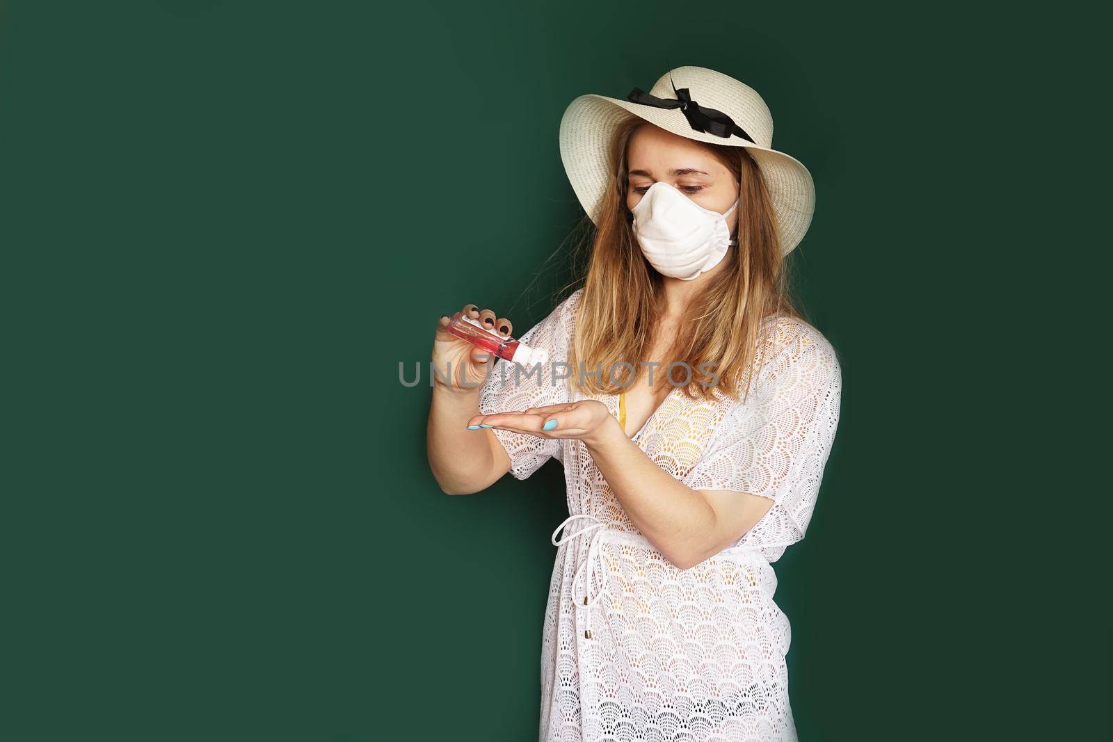 Beautiful girl in a white summer dress. Medical mask on the face. Closed borders during coronavirus. Tourist on a green background