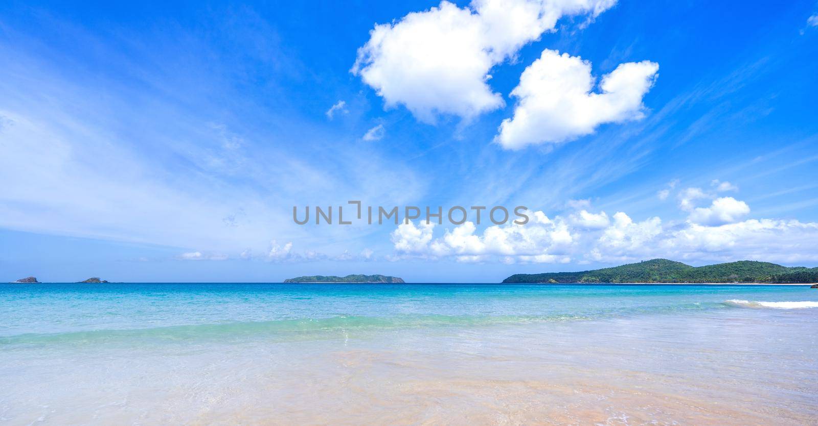 Beautiful amazing gold colored sandy beach with soft waves isolated with sunny blue sky. Concept of tropical calm tourism idea, copy space, close up