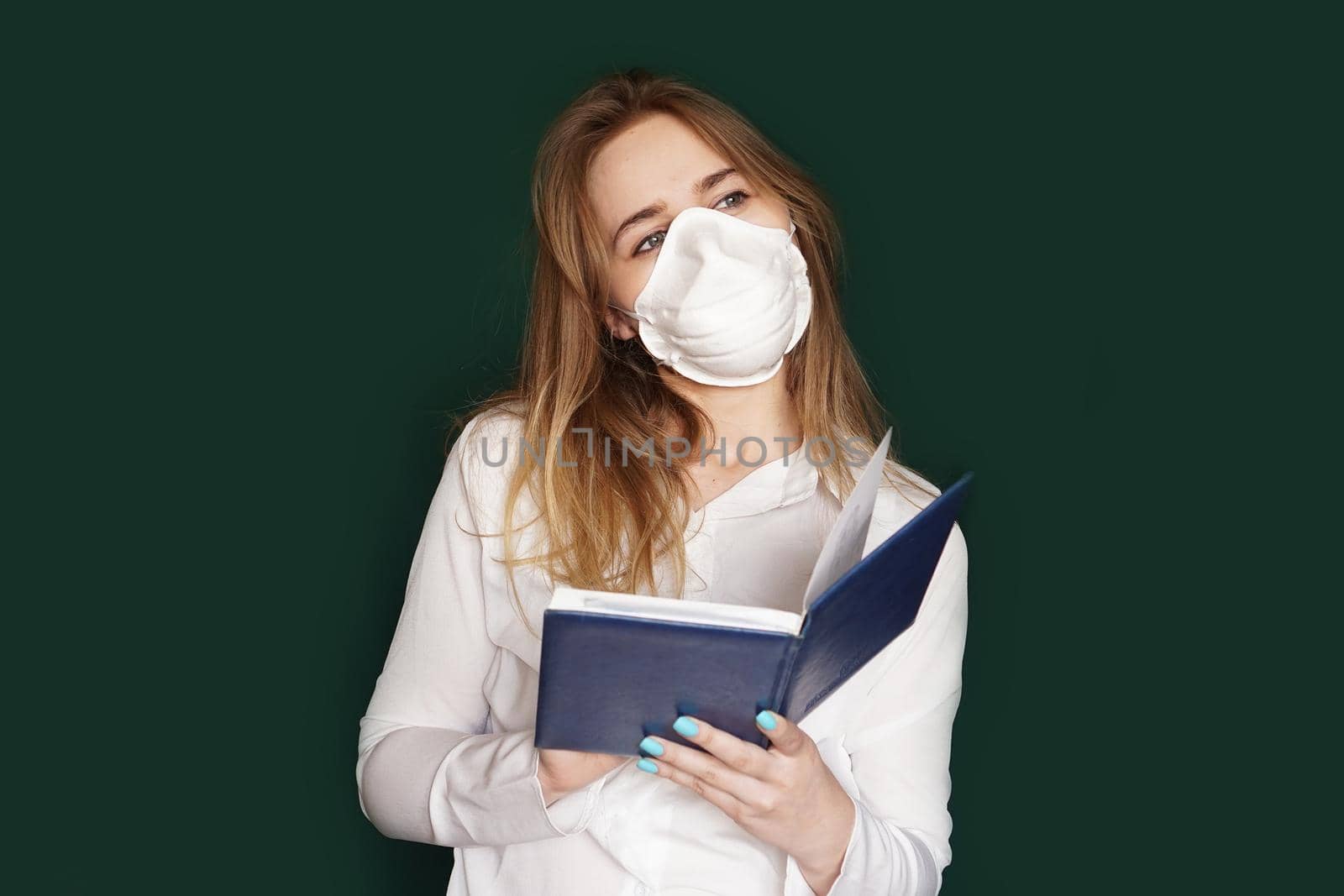 Young girl in a medical mask in a white office blouse with a notebook in hand by natali_brill