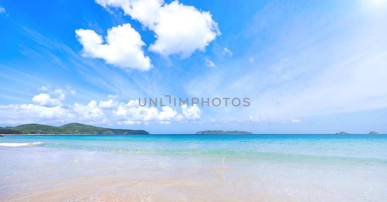 Beautiful amazing gold colored sandy beach with soft waves isolated with sunny blue sky. Concept of tropical calm tourism idea, copy space, close up
