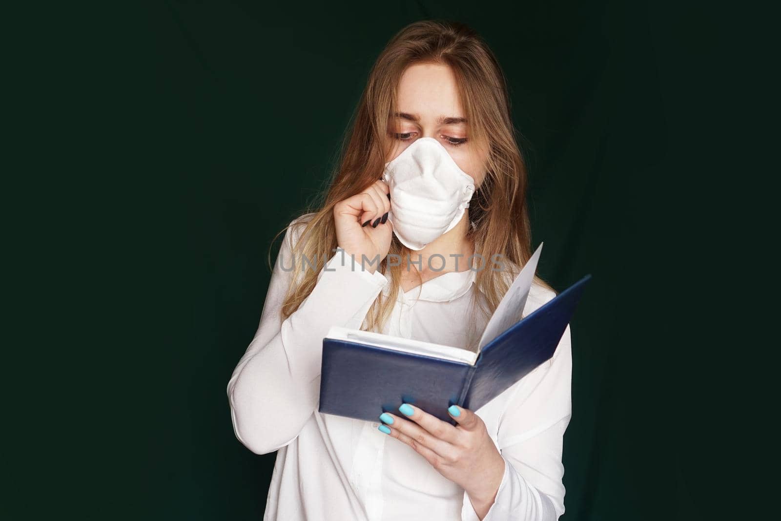 Young girl in a medical mask in a white office blouse with a notebook in hand by natali_brill