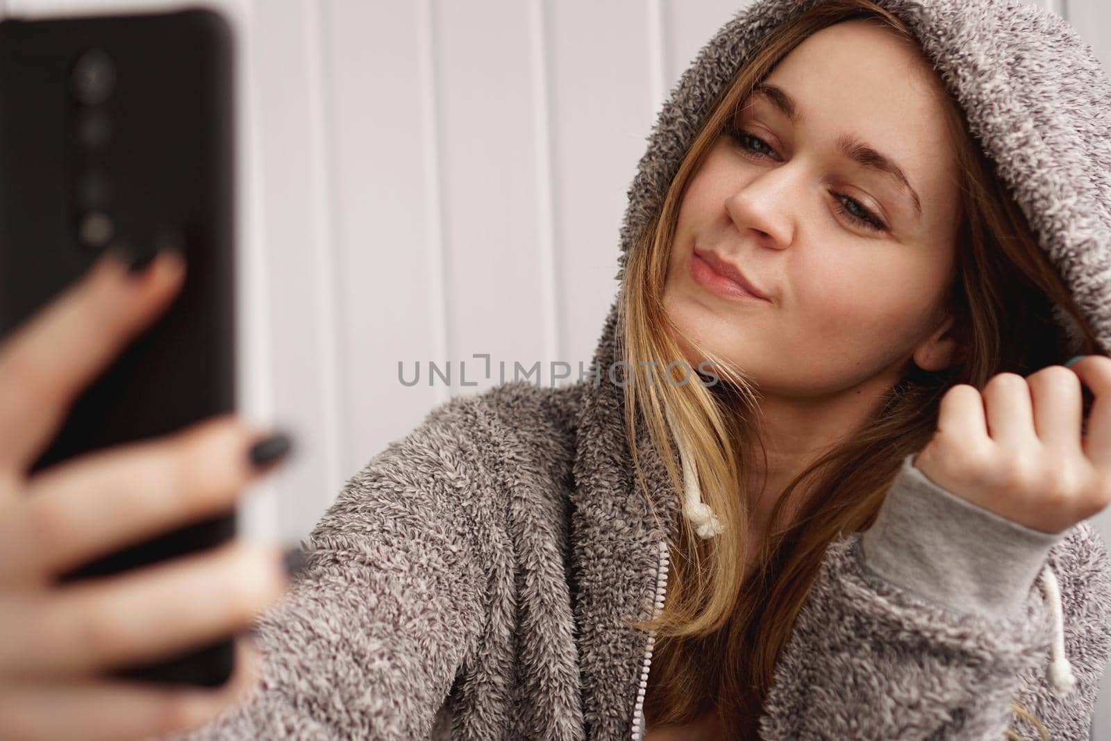 Picture of young happy emotional pretty lady indoors. Looking camera make selfie