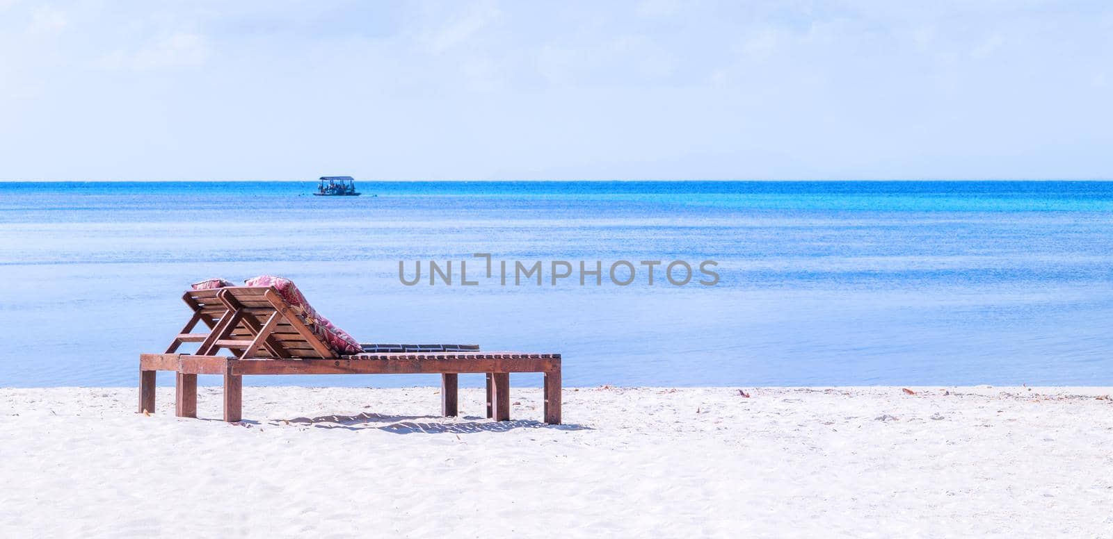 Chairs on the amazing beautiful sandy beach near the ocean with blue sky. Concept of summer leisure calm vacation for a tourism idea. Empty copy space, inspiration of tropical landscape